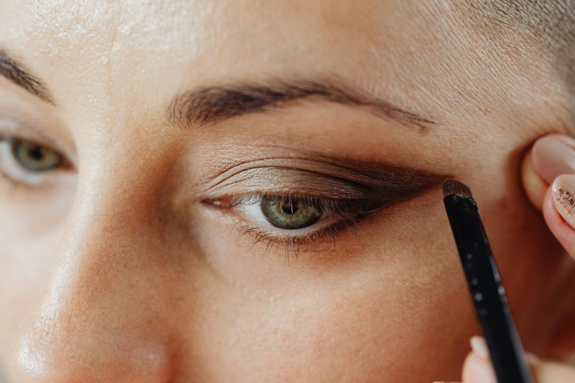 An woman applying eye shadow | Source: Pexels