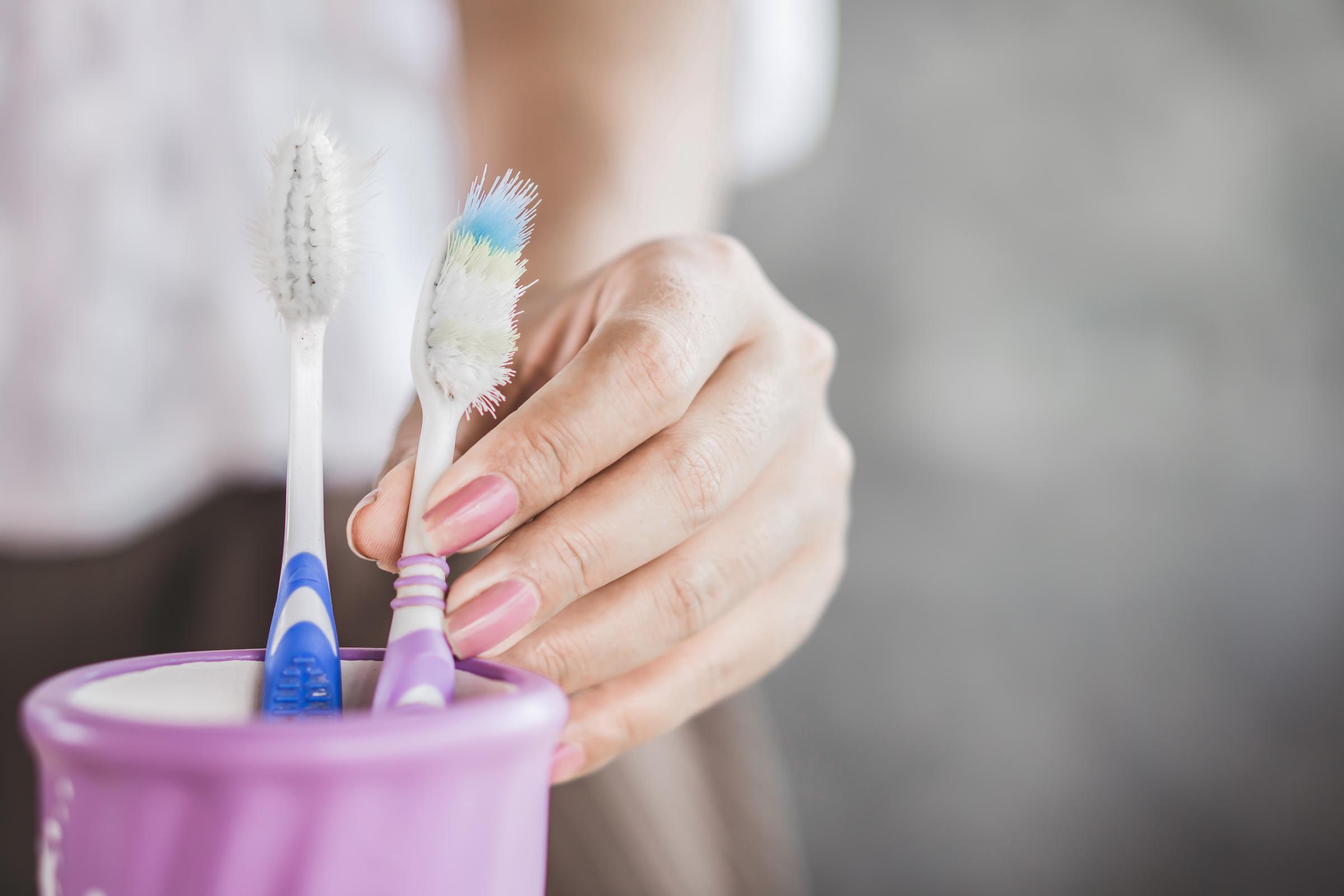 A woman grabbing an old toothbrush | Source: Getty Images
