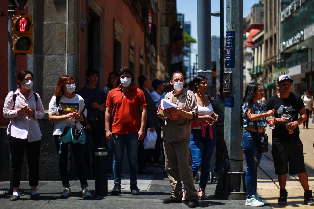 Personas con mascarillas esperan para cruzar una calle en el centro de la Ciudad de México el 26 de marzo de 2020. | Foto de Manuel Velásquez vía Getty Images