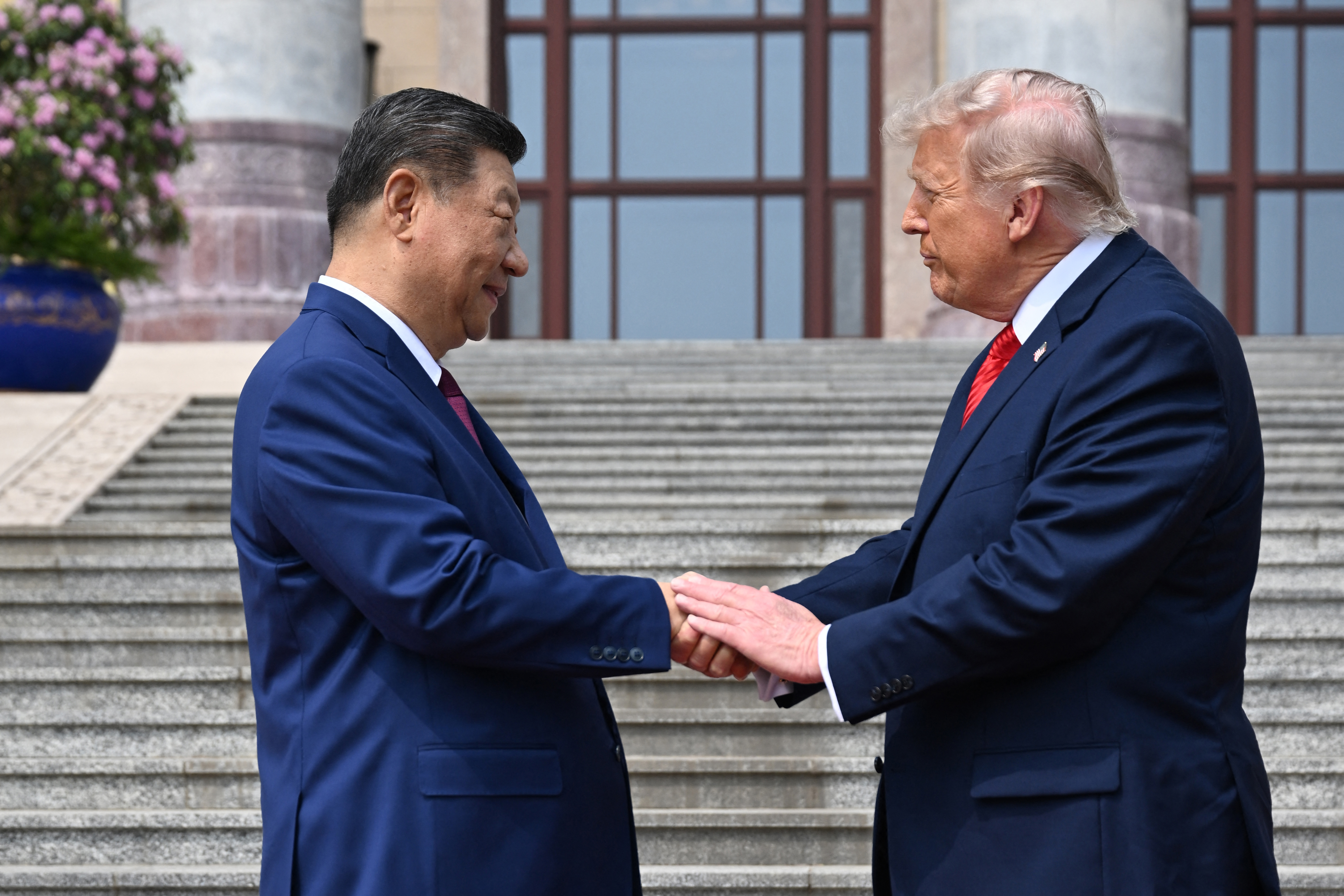 President Donald Trump, with his lips pursed, shakes hands with President Xi Jinping at the Great Hall of the People in Beijing on May 14, 2026. | Source: Getty Images