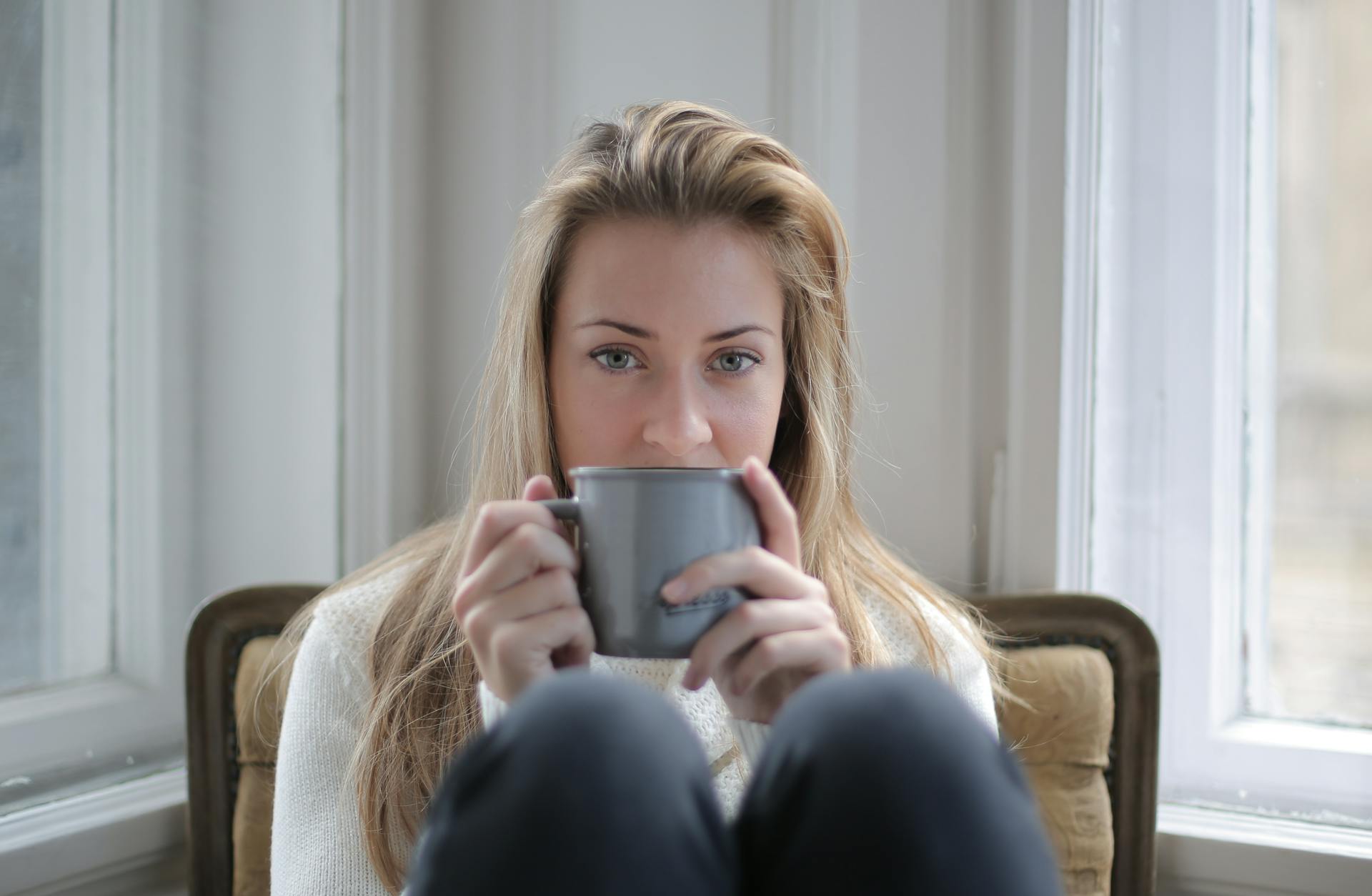 A woman sitting in a chair while holding a coffee mug | Source: Pexels