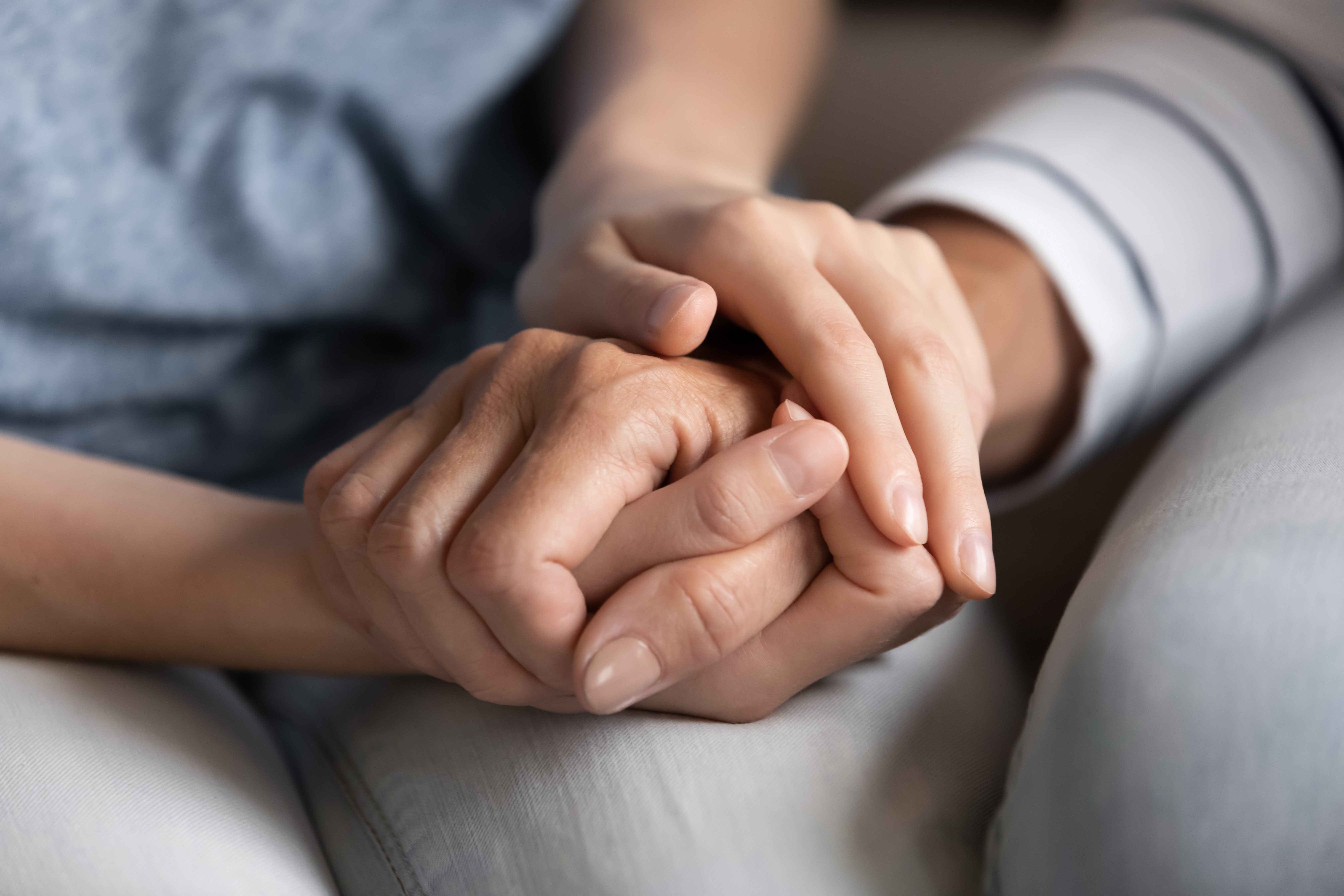 Close up of millennial woman grown daughter, grandchild or younger friend holding tight hand of old mother, grandmother, elder relative or colleague helping to overpass life problems. | Source: Shutterstock