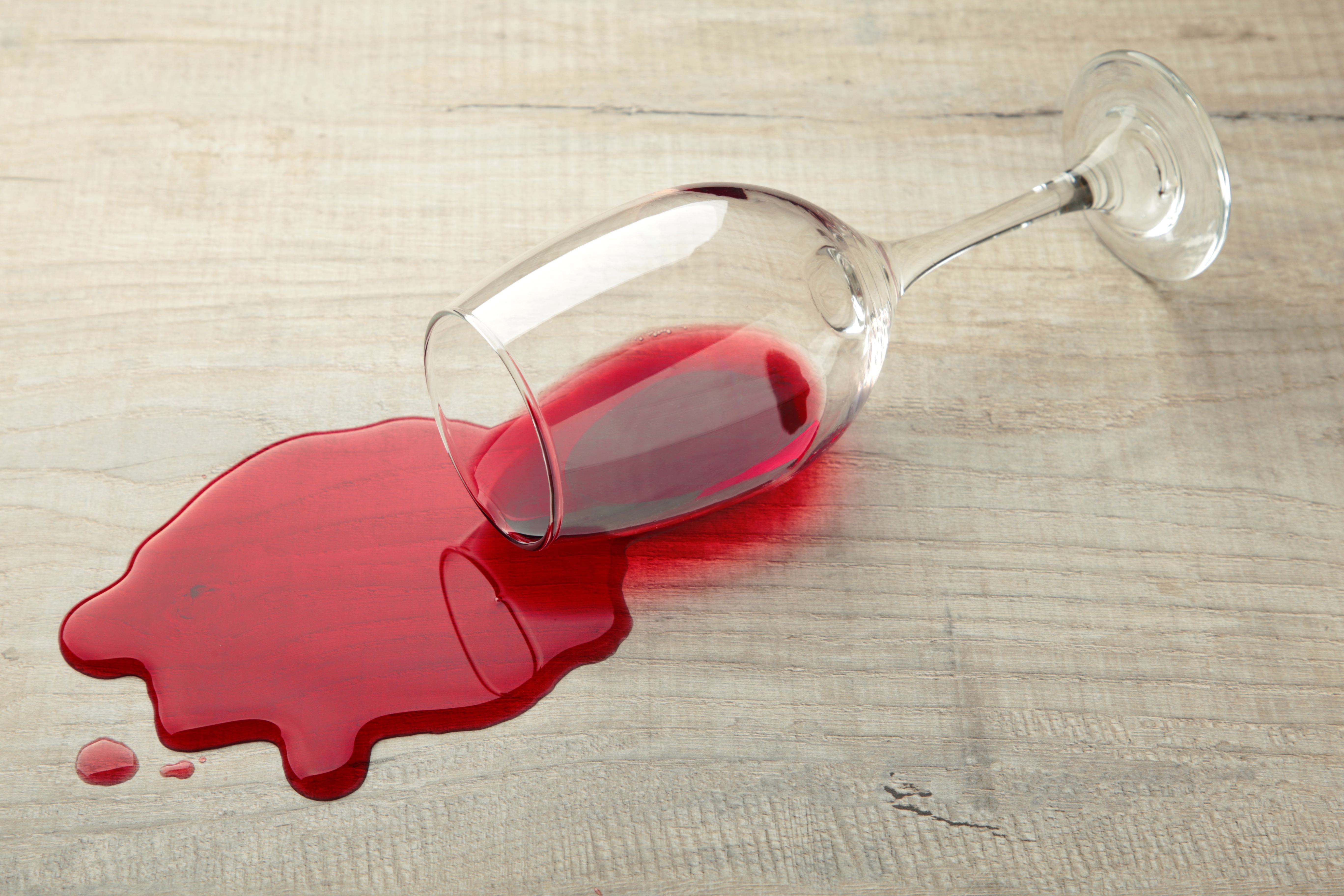 Glass of red wine fell on laminate, wine spilled on floor. | Source: Shutterstock