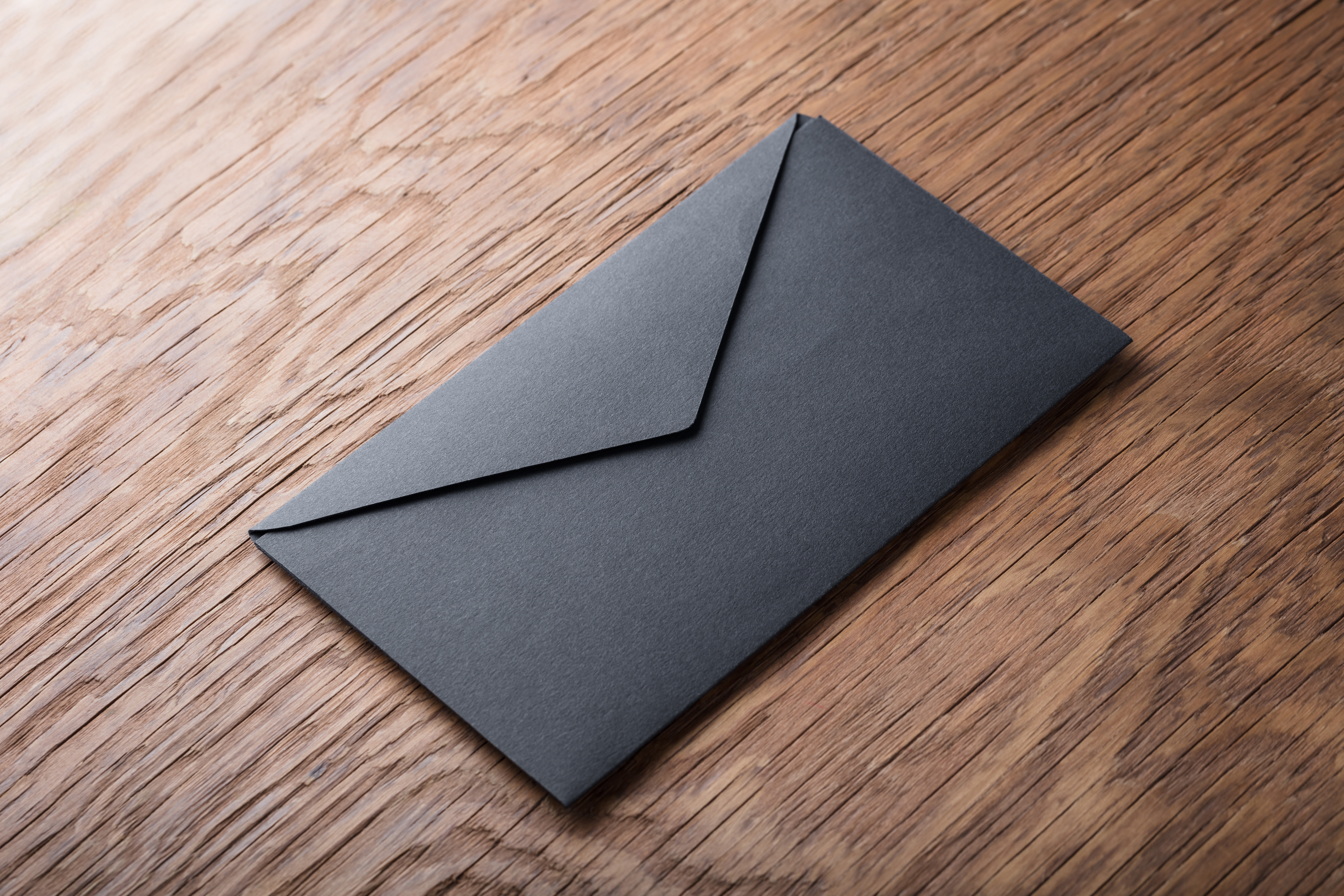 Black envelope on wooden table | Source: Shutterstock