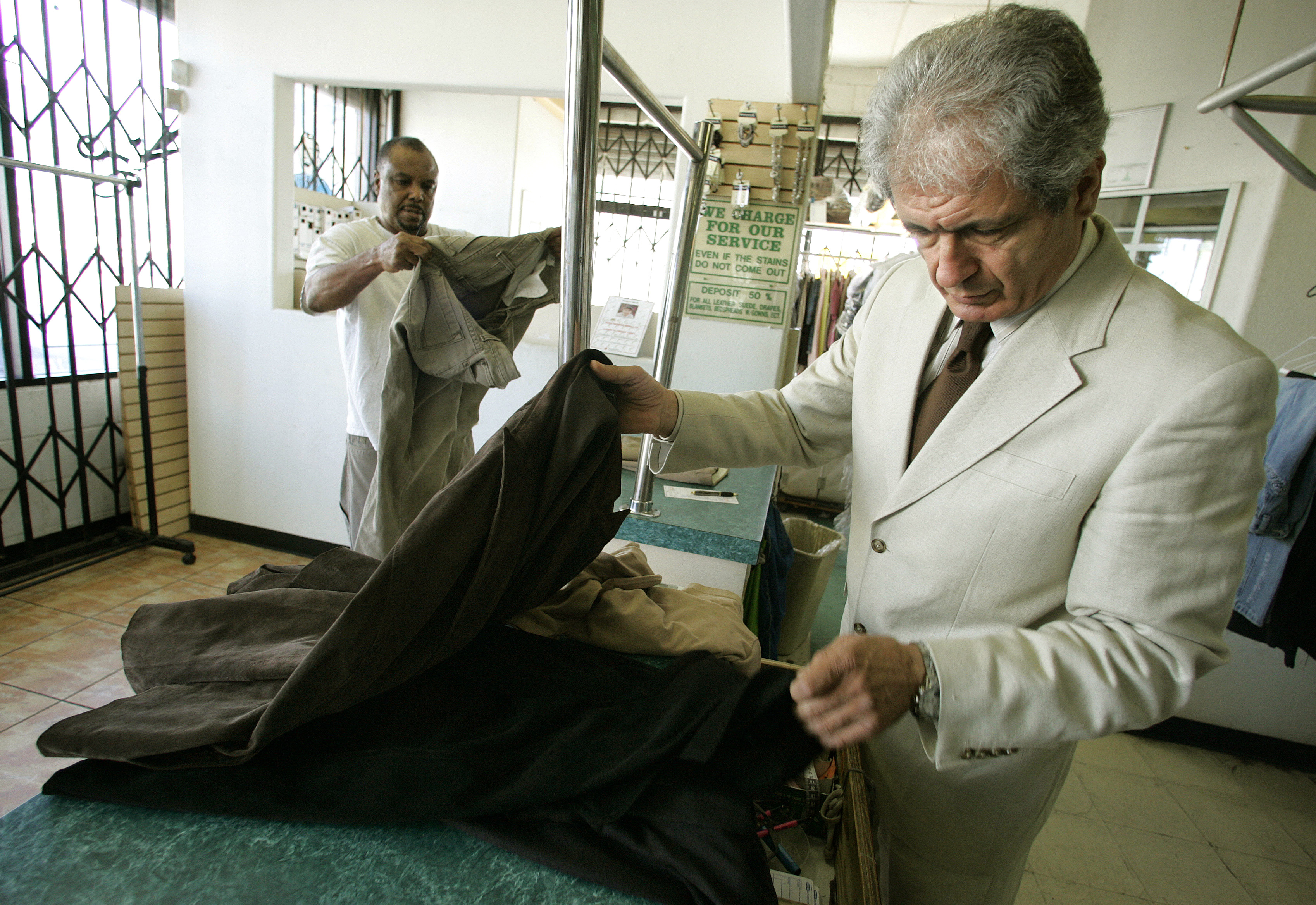 Owner of Park Lane Cleaners in Los Angeles inspects a customer's clothes | Source: Getty Images