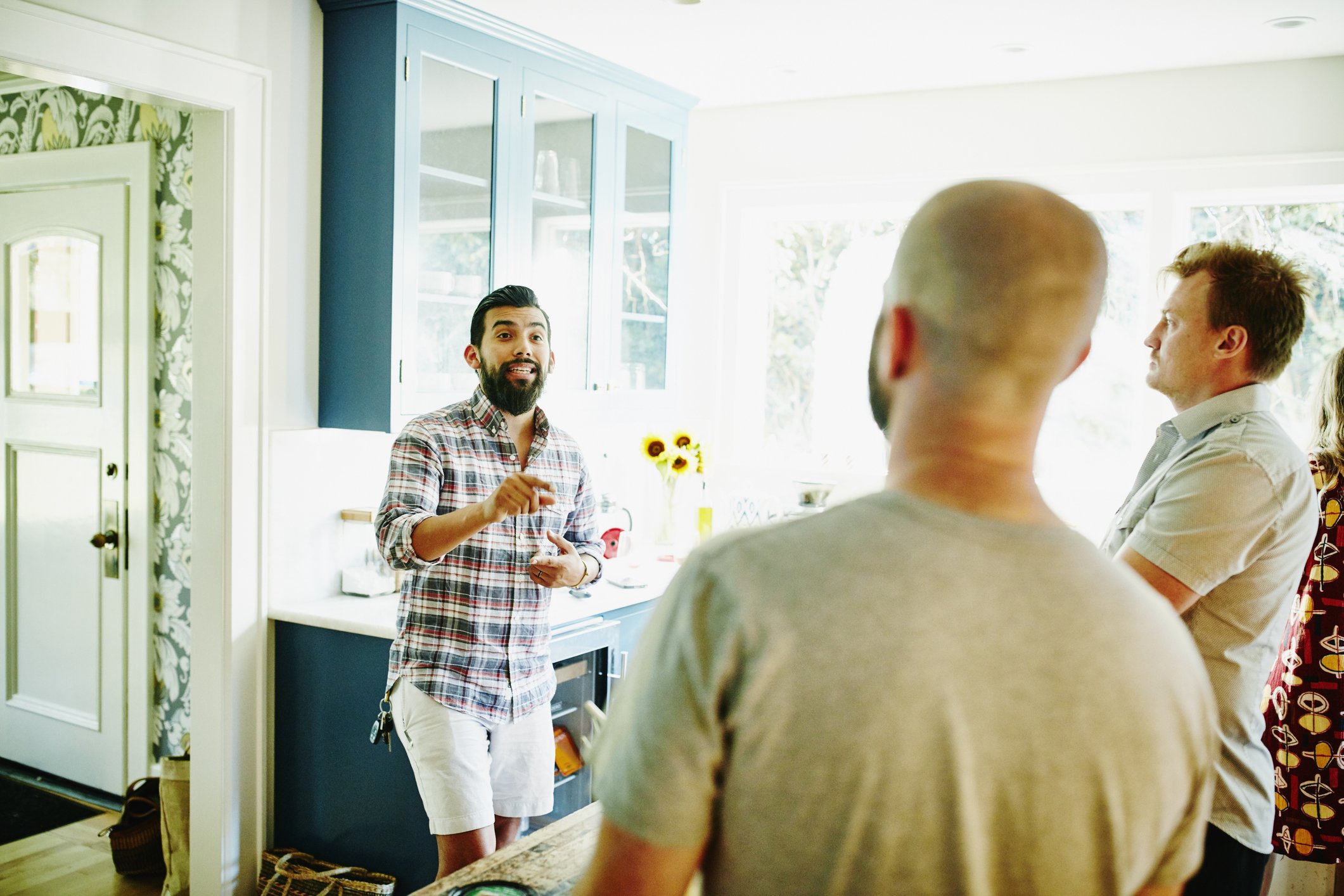 Man in discussion with friends in kitchen  | Photo: Getty Images