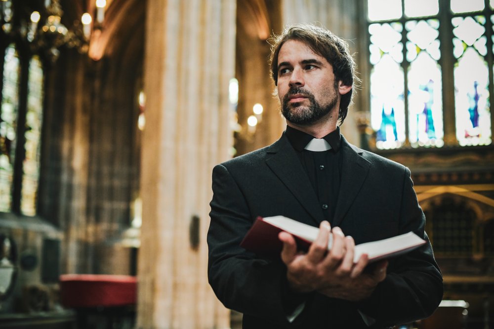 A photo of a young priest standing by the altar. | Photo: Shutterstock