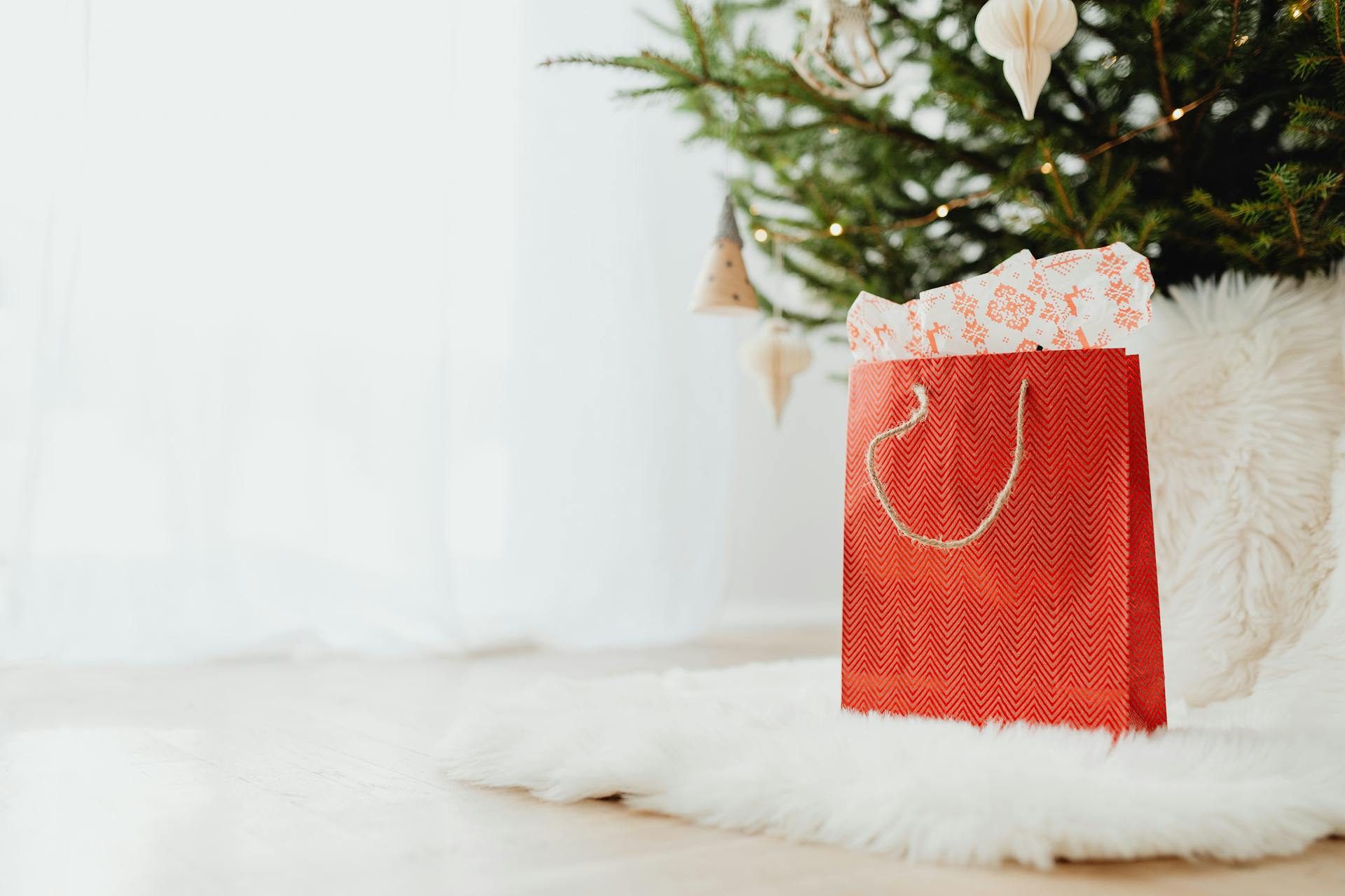 A red gift bag lying on a white fur carpet | Source: Pexels