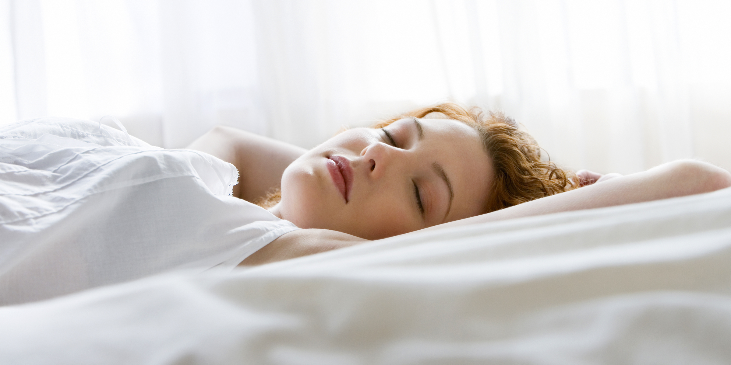 A beautiful young woman, bathed in soft light, sleeping peacefully | Source: Getty Images