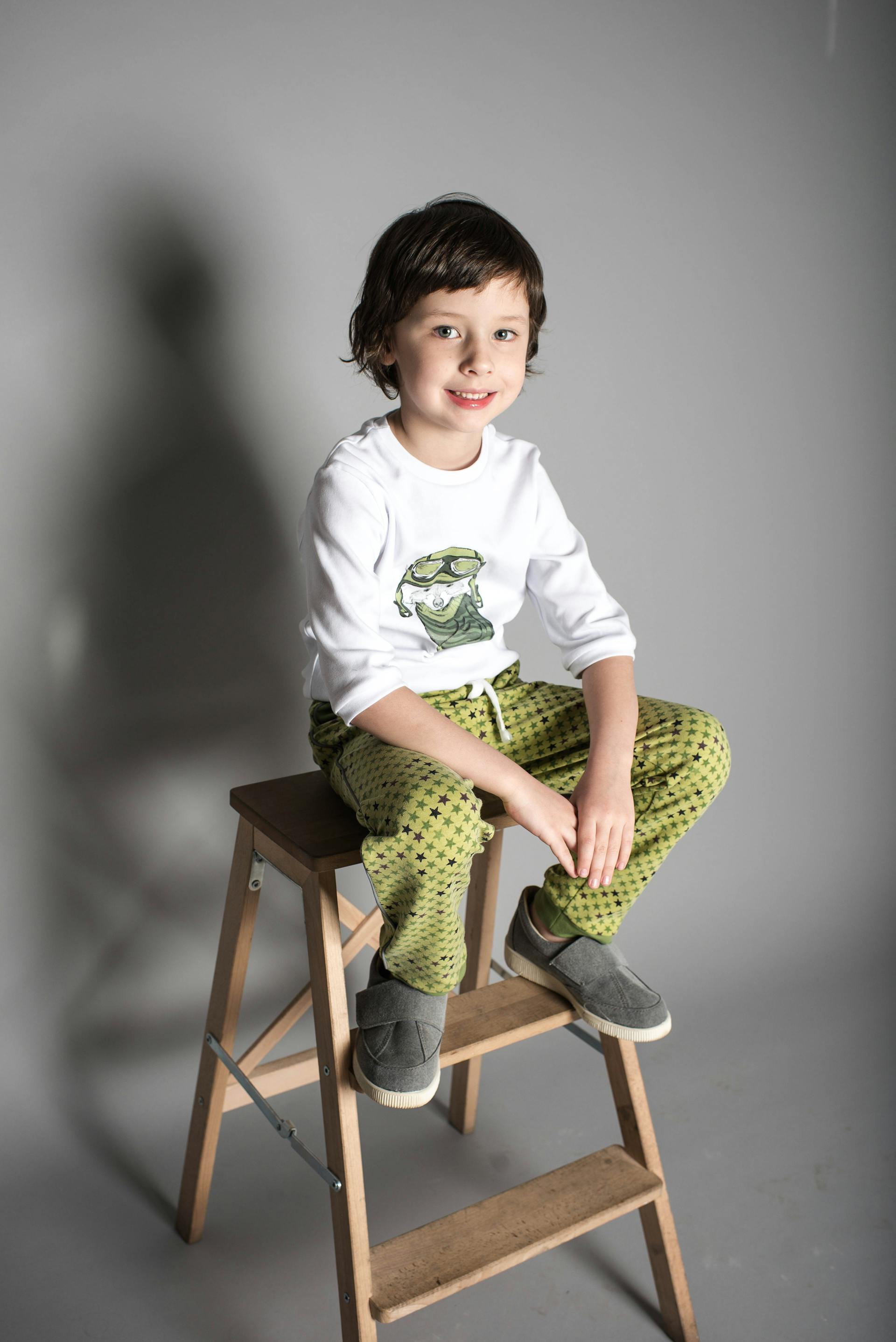 A little boy sitting on wooden A-frame steps | Source: Pexels