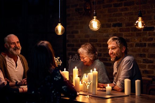 Photo of relaxed family group enjoying candlelit dinner together | Photo: Getty Images