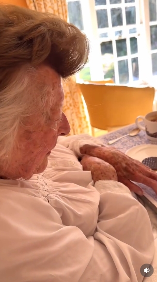 Turning slightly toward her tray, Lady Pamela Hicks appears focused and content, her posture relaxed as she prepares to enjoy her morning coffee. The scene is framed by warm tones and elegant furnishings, reinforcing the sense of calm and understated luxury that defines the setting. | Source: Instagram/indiahicksstyle
