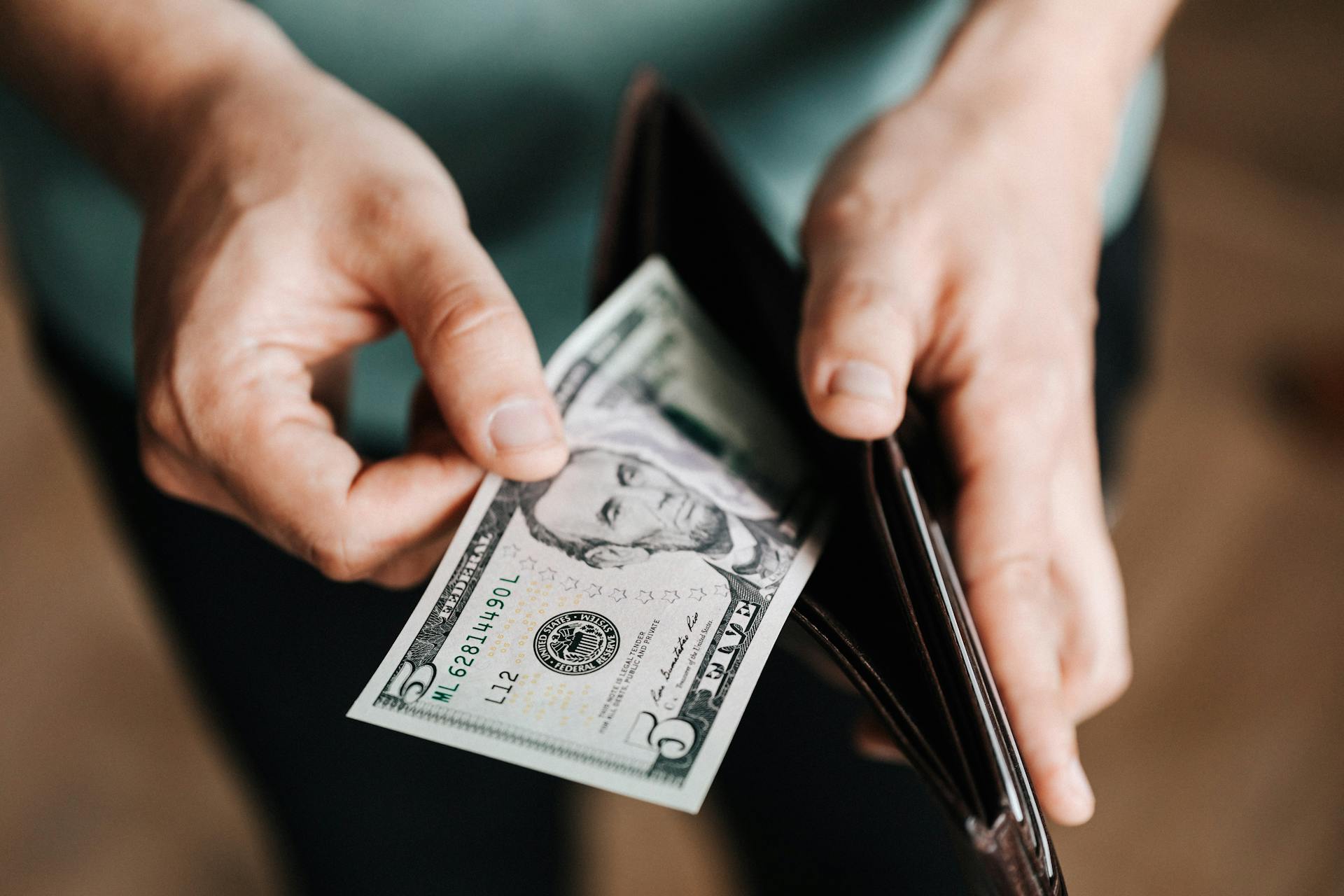 A man putting cash in his wallet | Source: Pexels