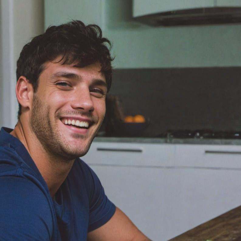 A man seated at a kitchen island, smiling widely | Source: Midjourney