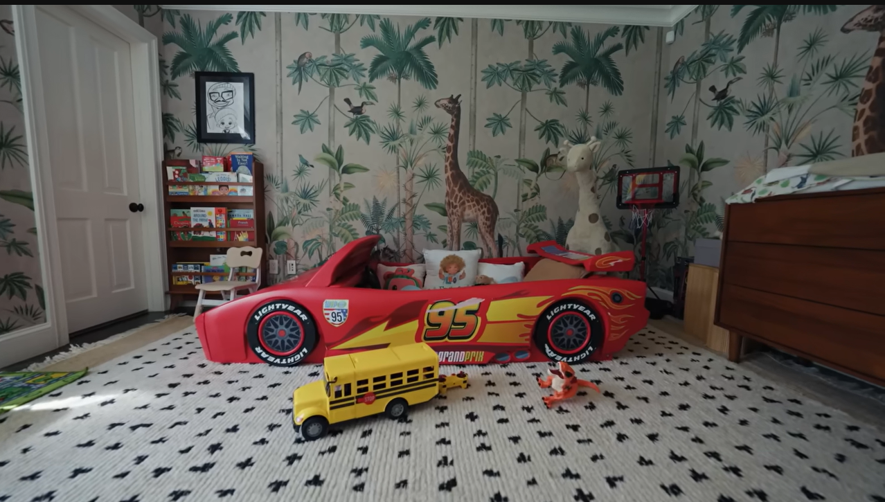 Floor-to-ceiling style! The fun bedroom layout beautifully pairs wild safari wallpaper with toy cars and dinosaurs. | Source: YouTube/@Archdigest
