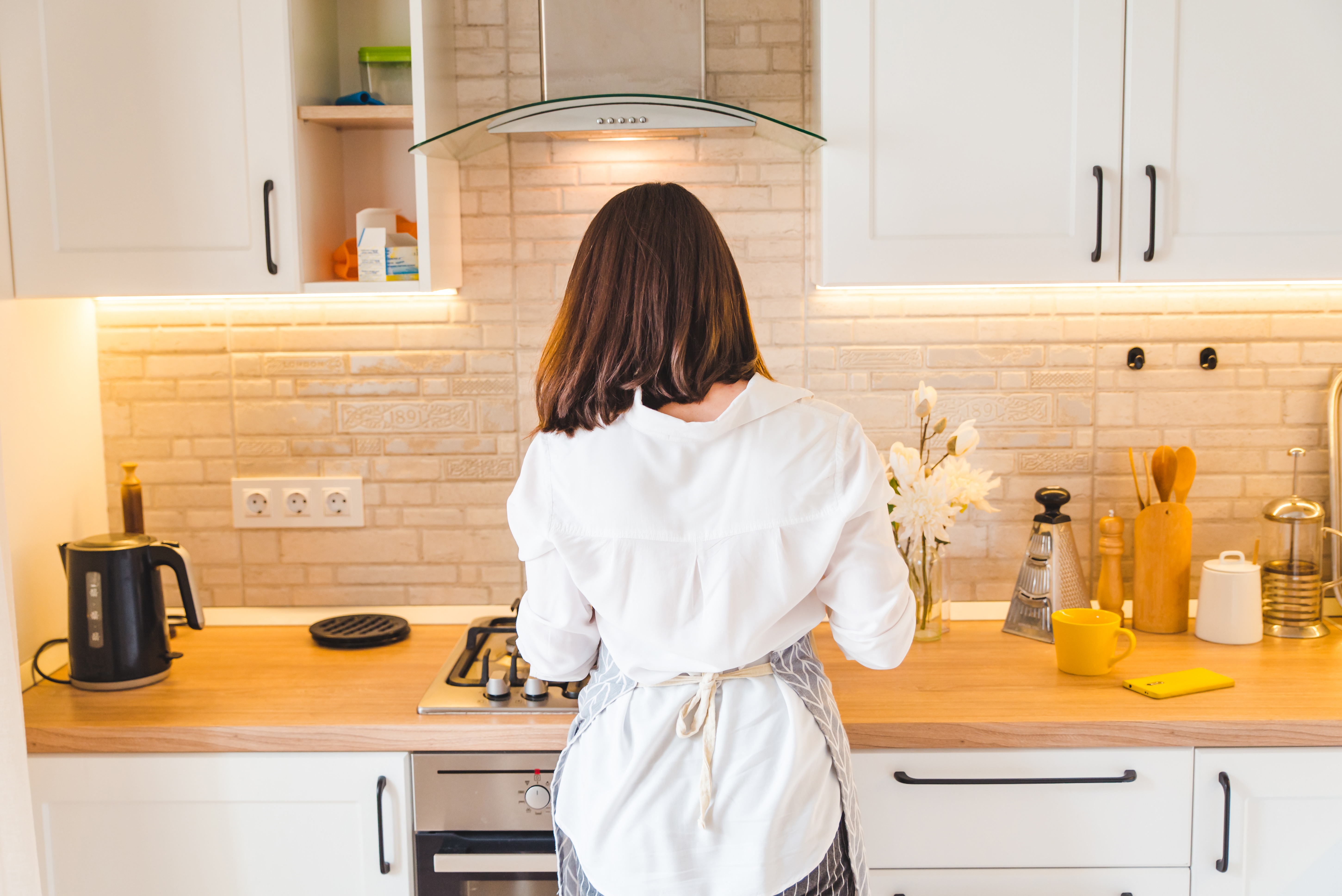 View from behind woman on kitchen cooking housewife. | Source: Shutterstock