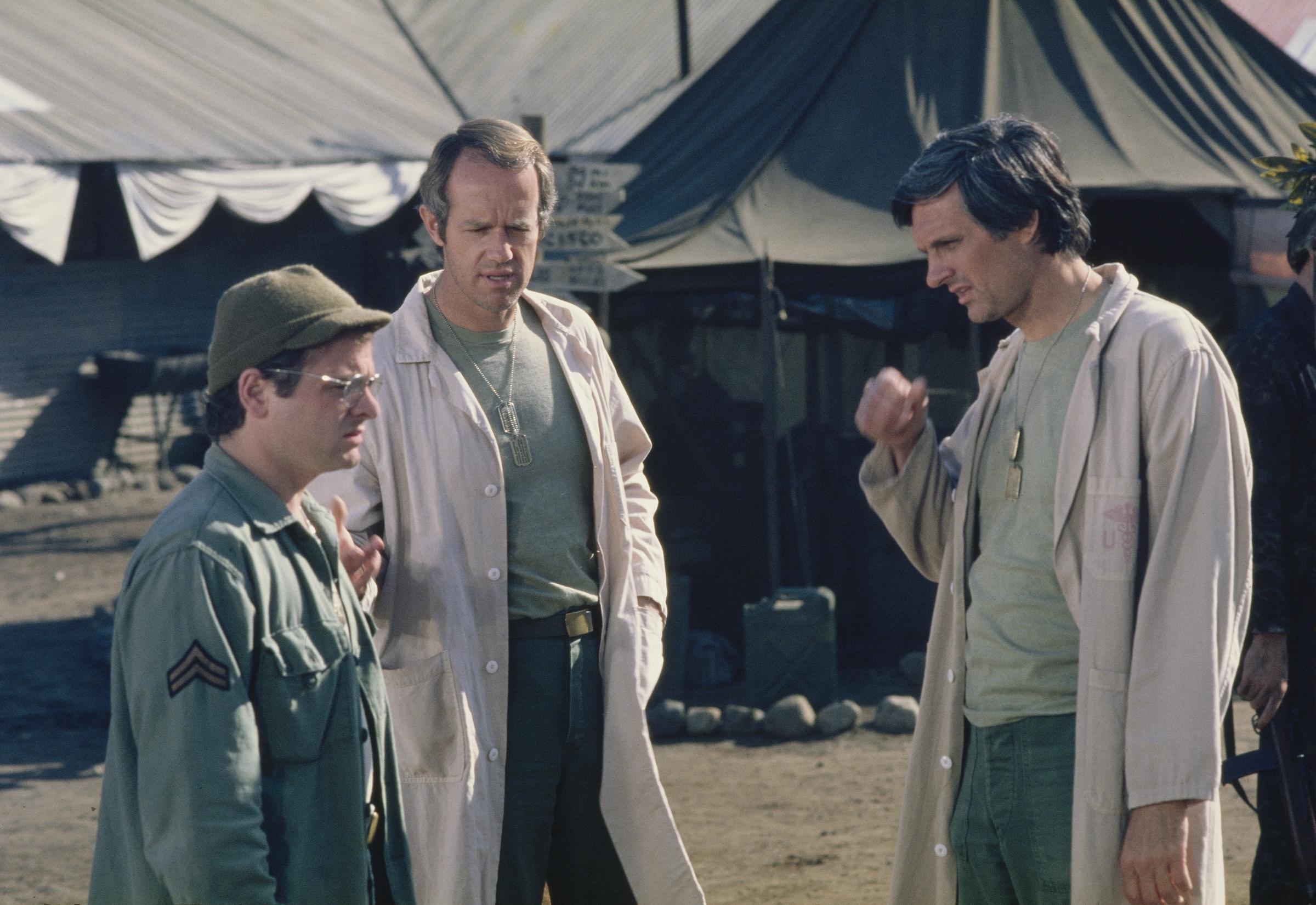 Gary Burghoff, Mike Farrell, and Alan Alda during the filming of the television show "M*A*S*H," circa August 1976 | Source: Getty Images