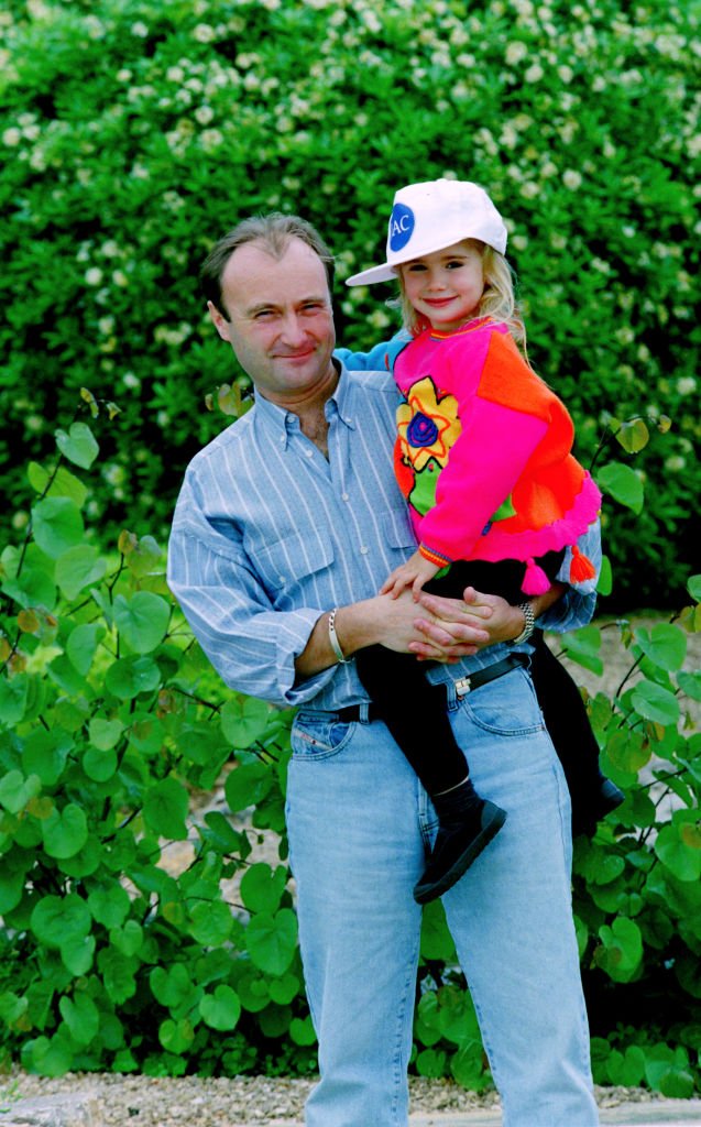 Portrait du musicien Phil Collins (à gauche) avec sa fille Lily Collins, lors d'une tournée au Japon, vers 1988. | Photo : Getty Images