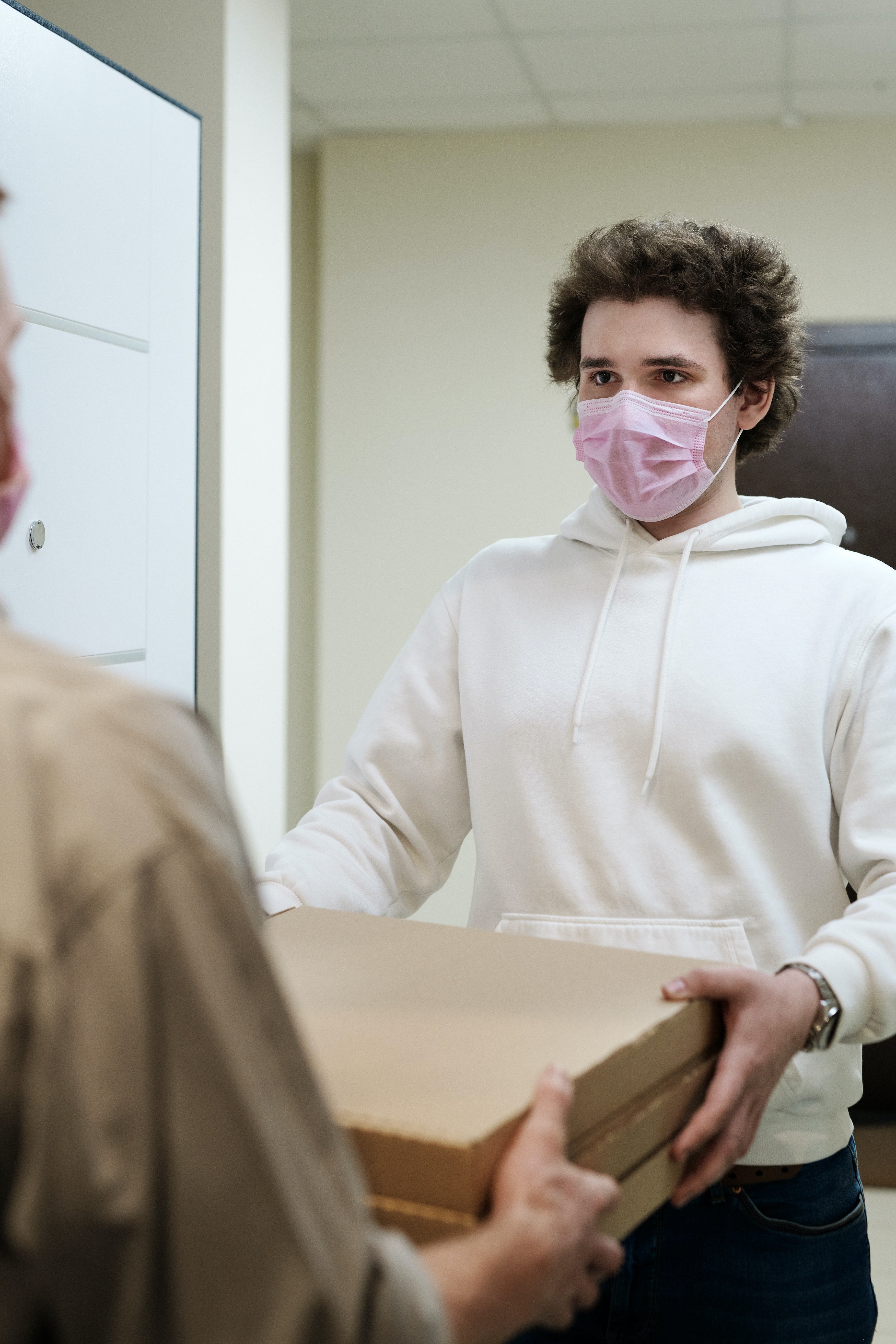 Man in a face mask receiving a pizza delivery | Photo: Pexels