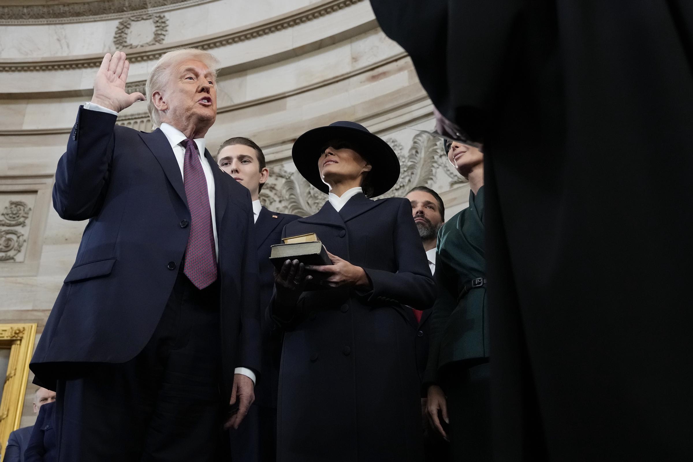 Donald Trump taking an oath of office from Chief Justice John Roberts as Barron and Melania Trump look on. | Source: Getty Images