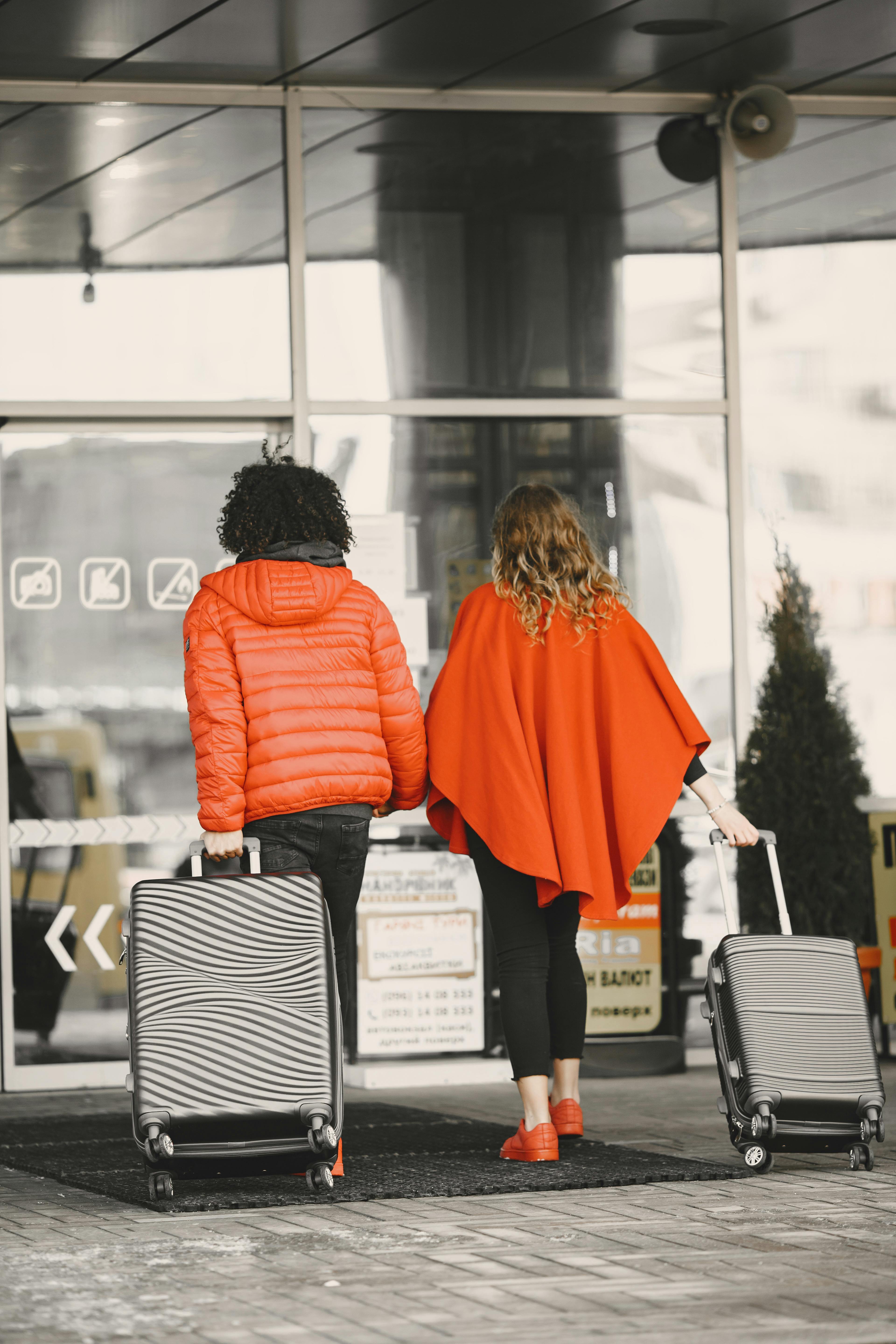 A couple dragging their luggage as they enter an airport | Source: Pexels