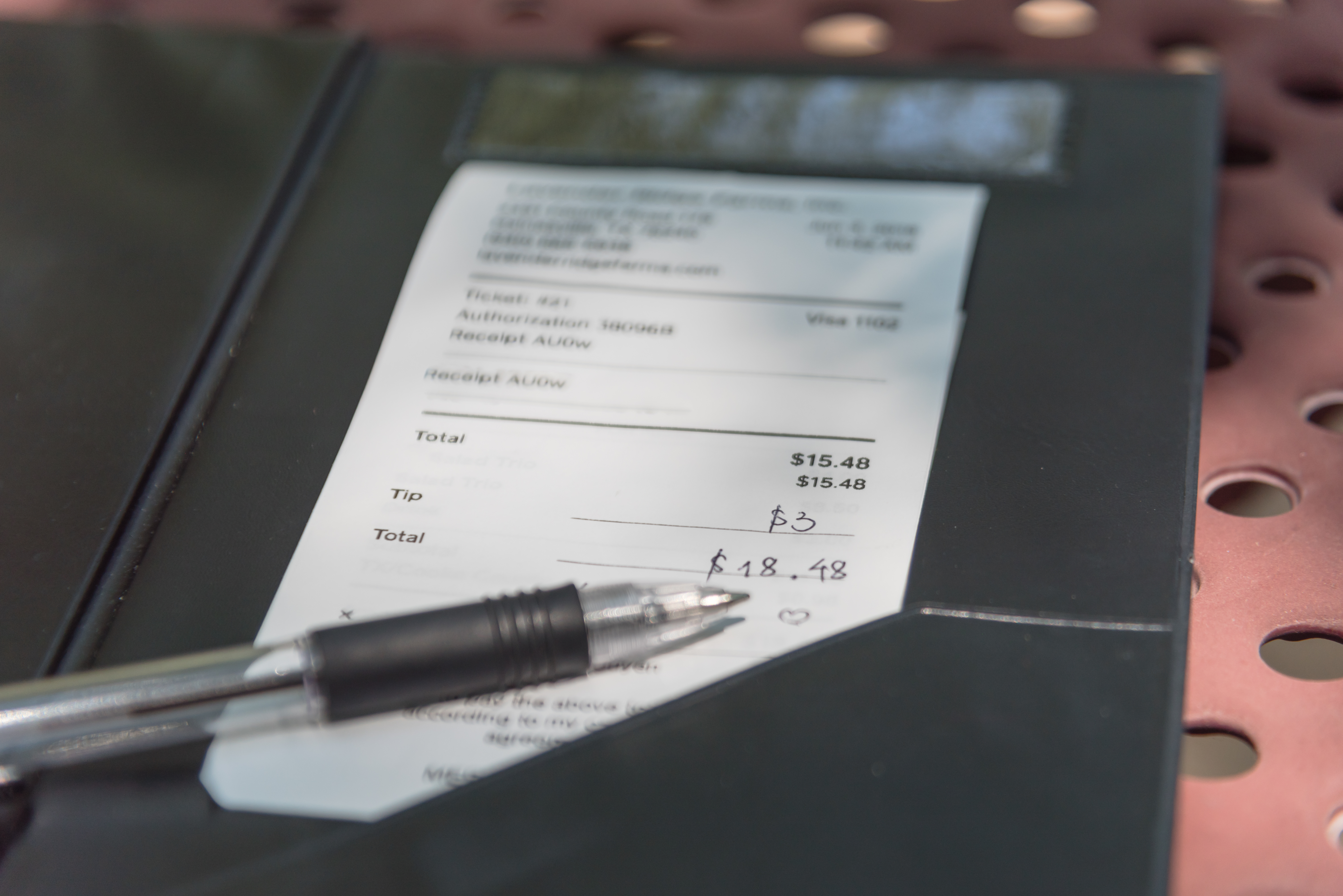 An open leather bill holder with restaurant check and pen | Source: Shutterstock