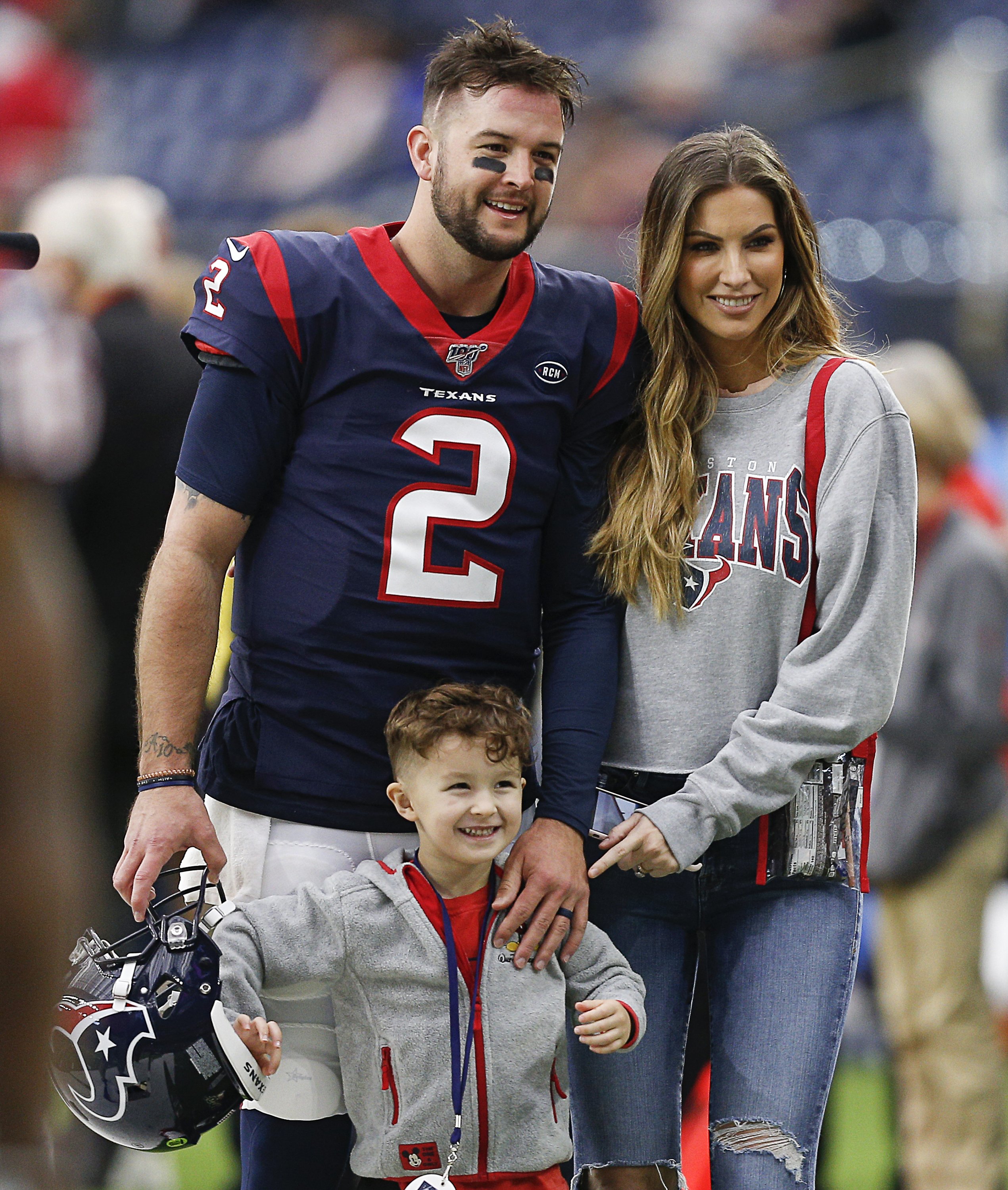 A.J. McCarron, his wife Katherine Webb, and their eldest son, Tripp, pose for a picture on the sidelines before a football match against the Tennessee Titans at NRG Stadium on December 29, 2019, in Houston, Texas. | Source: Getty Images