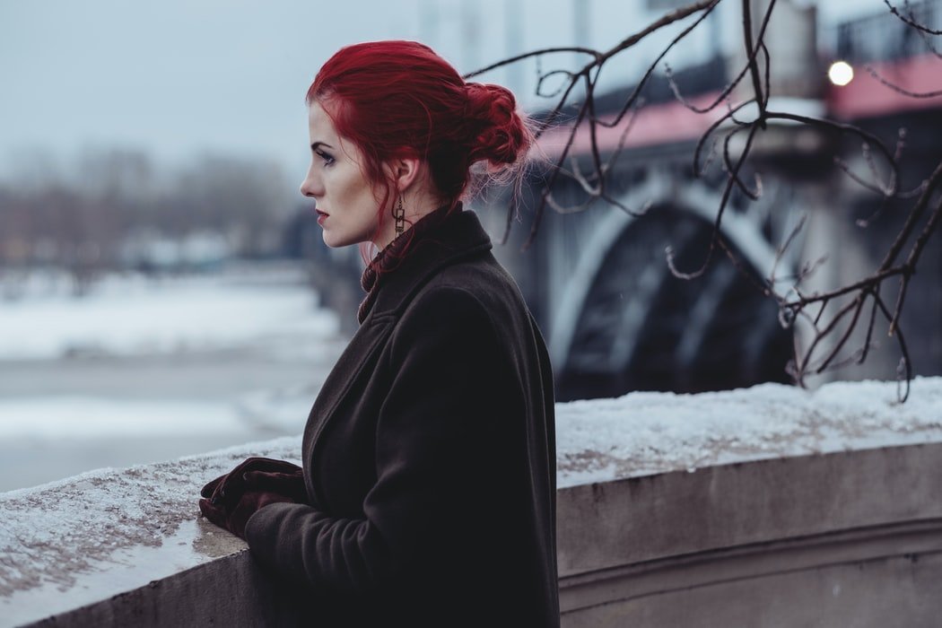 A woman who is deep in thoughts stares at a landscape | Photo: Unsplash