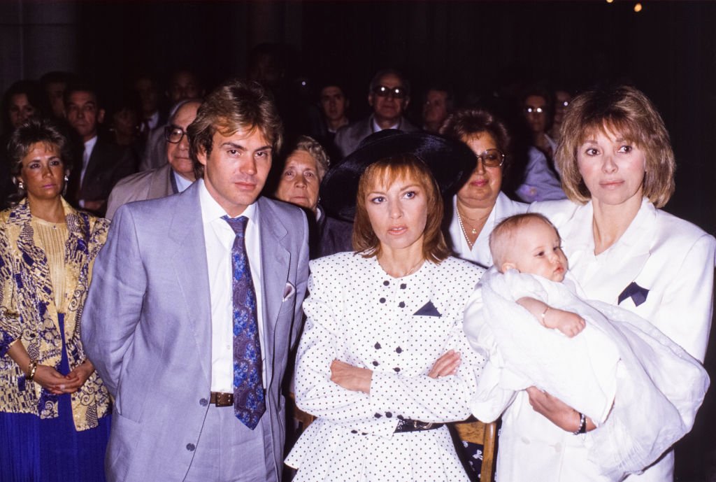 Les parents de Jeremy, François Valéry et Nicole Calfan, et leur enfant dans les bras de Mireille Darc en mai 1987 à Neuilly-sur-Seine, France. | Photo : Getty Images