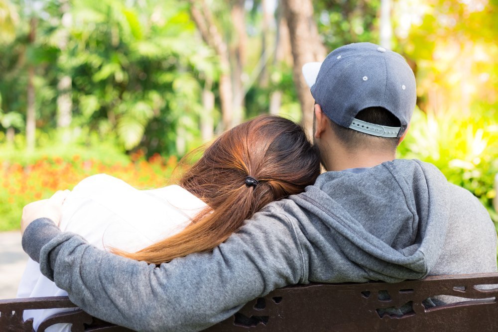 Lovely couple sit in park. Charming beautiful girlfriend lay her head on her boyfriend’s shoulder | Photo: Shutterstock