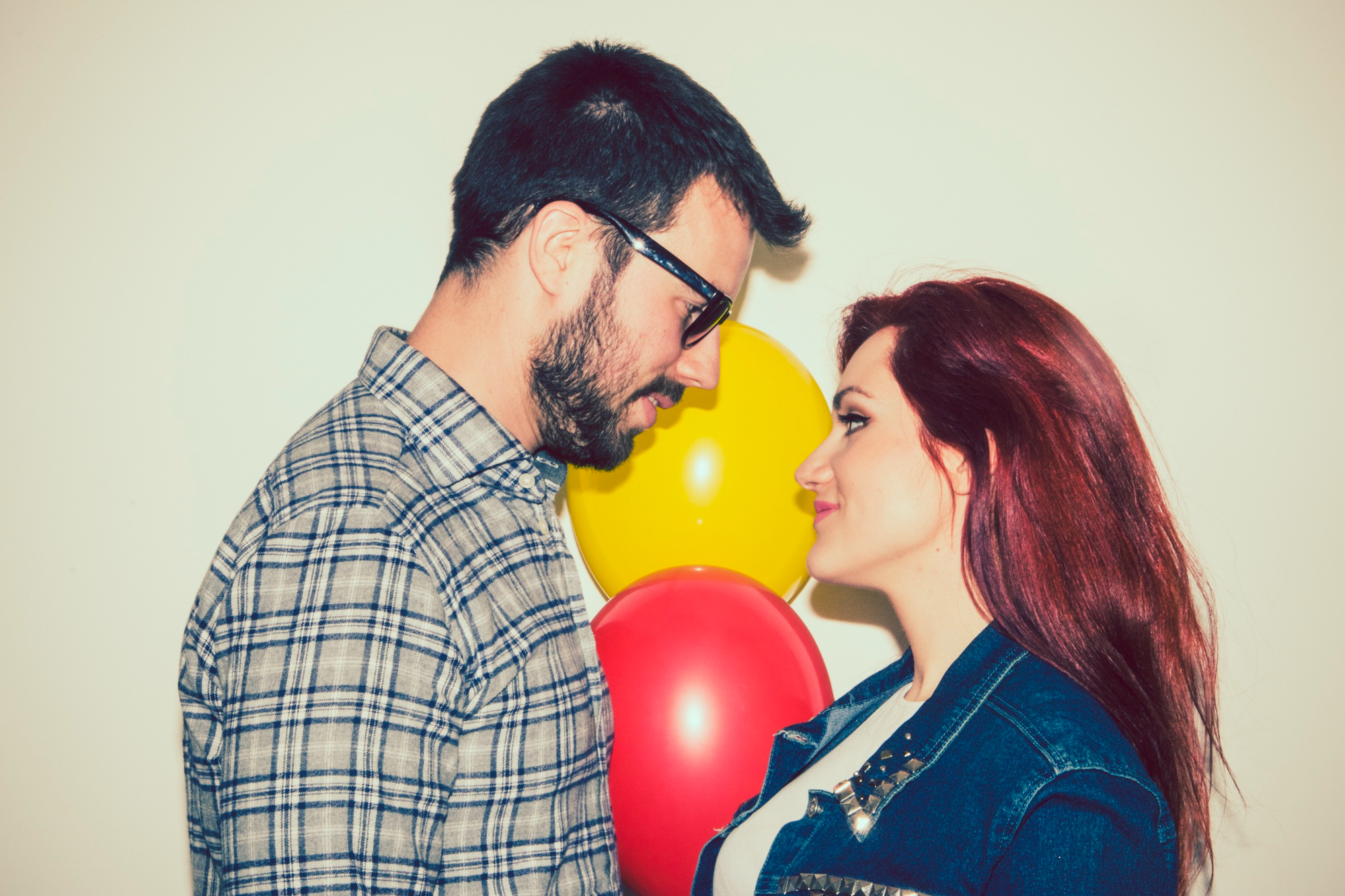A couple looking at each other with balloons in the background | Source: Freepik