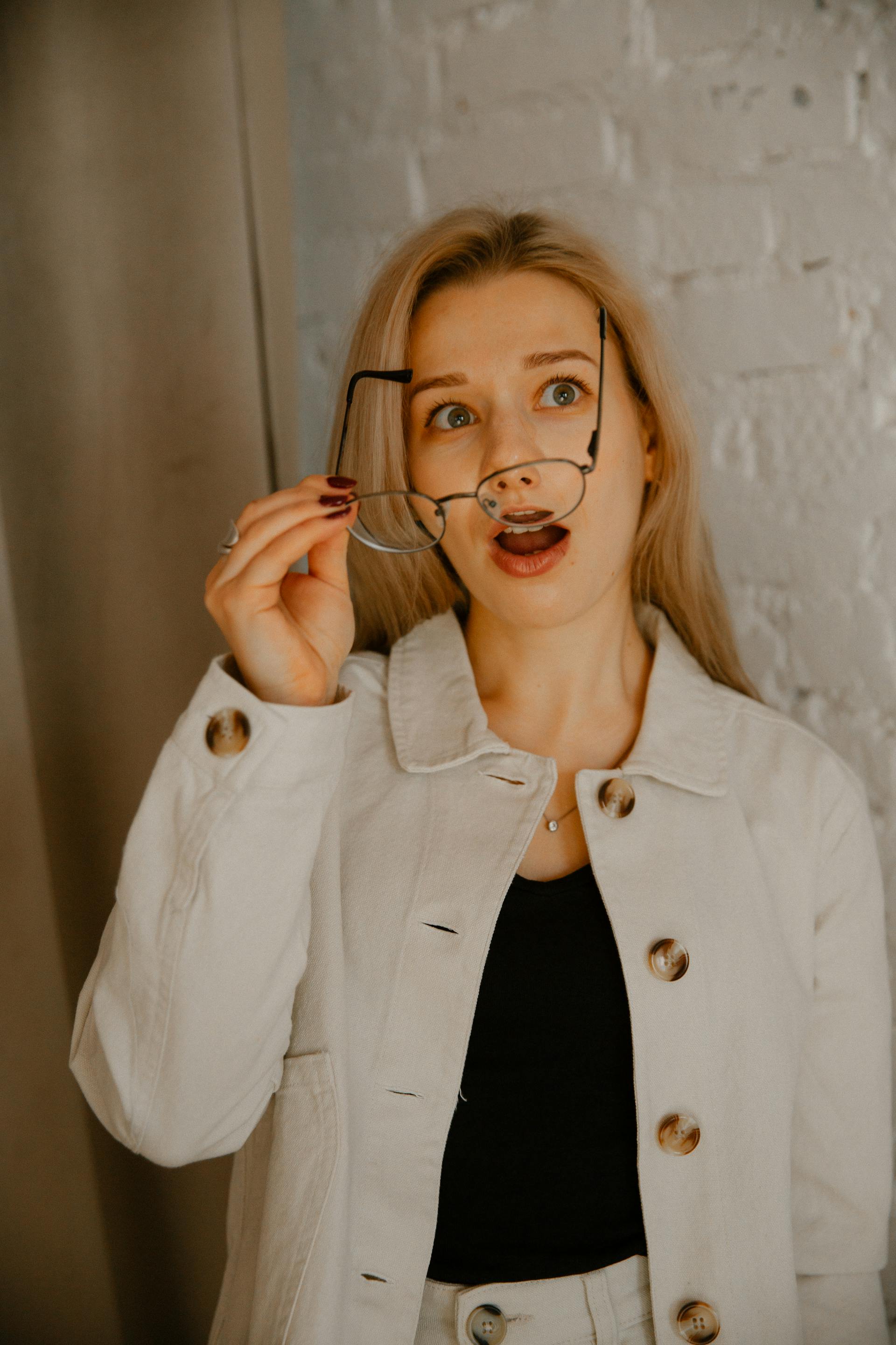 A surprised woman taking off her eyeglasses | Source: Pexels