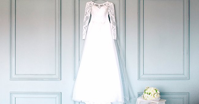 A wedding dress hanging from a wall. | Image: Shutterstock.