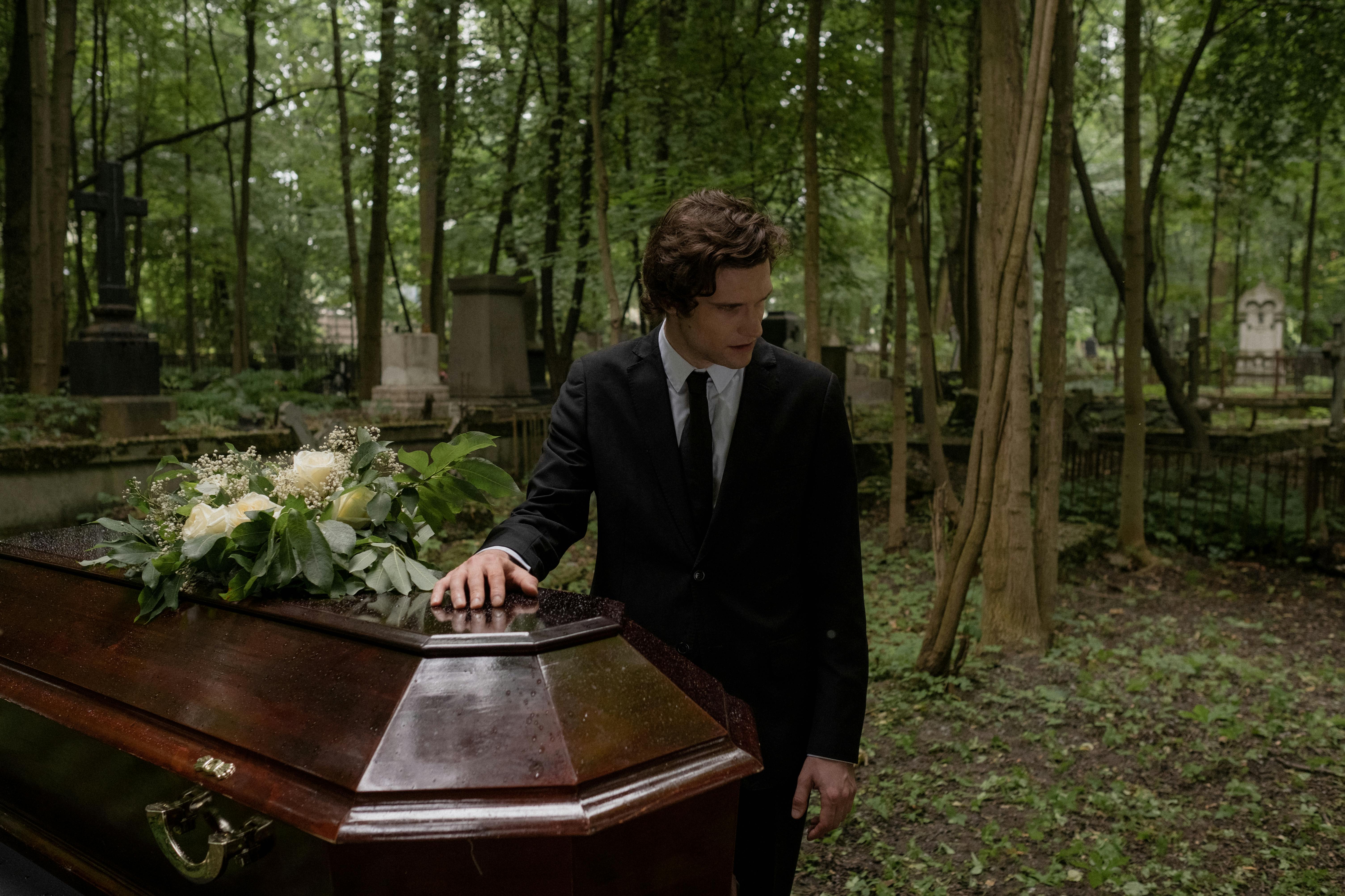 A man placing his hand on a coffin | Source: Pexels