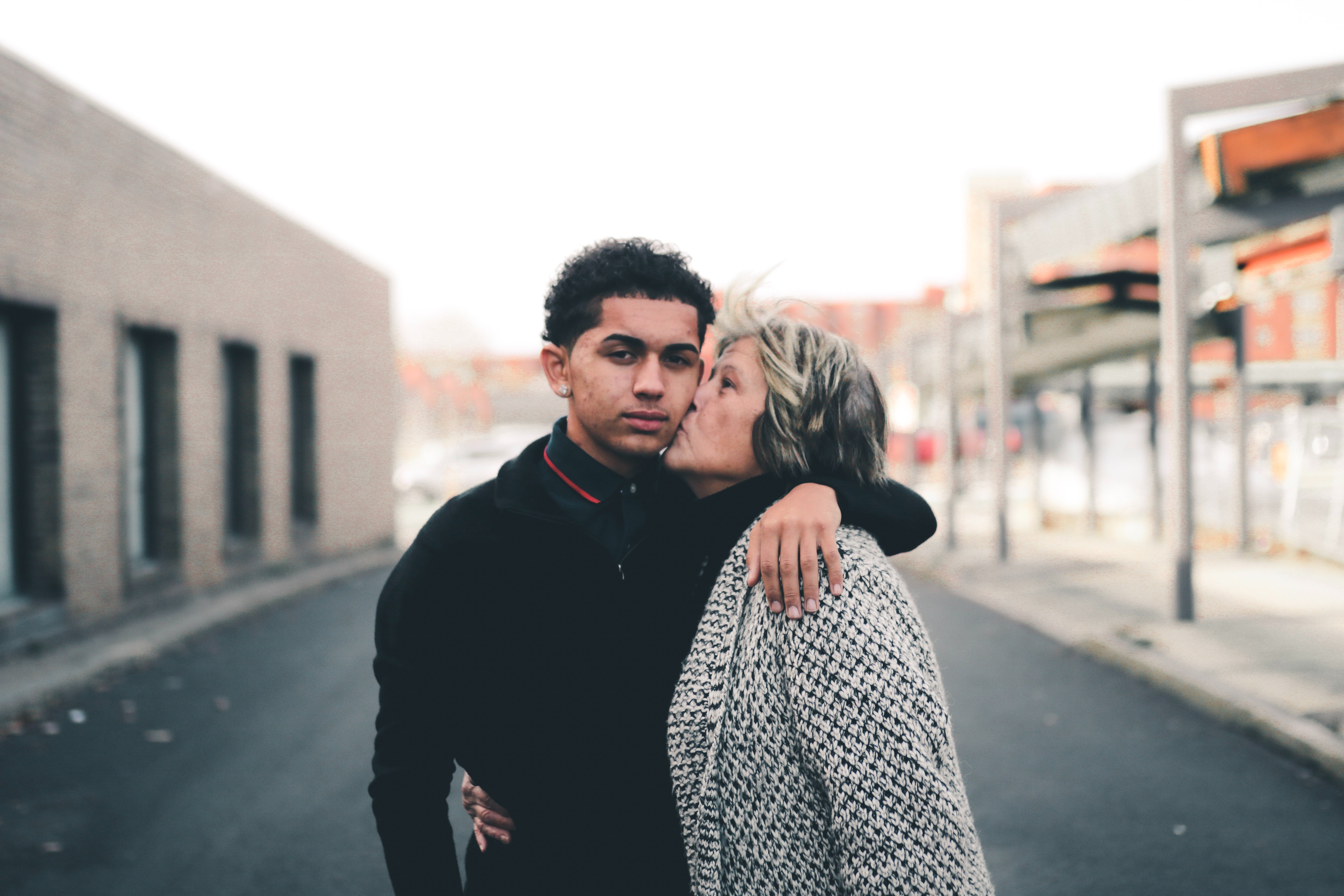 A young man receiving a kiss on the cheek from an older woman | Source: Pexels