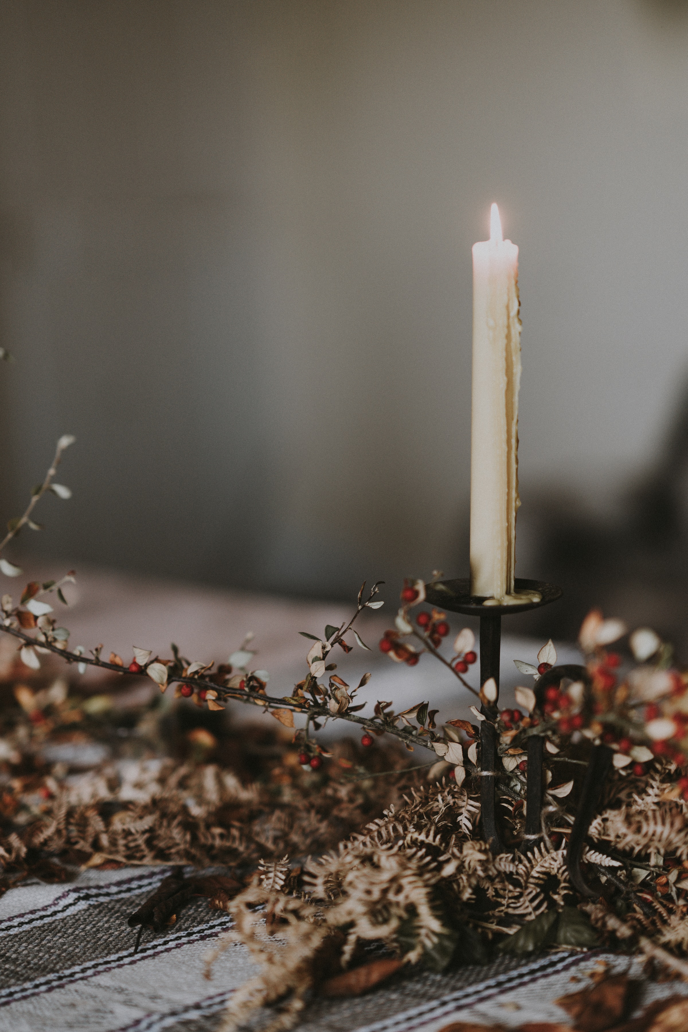 A lighted candle on a candlestick is placed on a table | Source: Unsplash