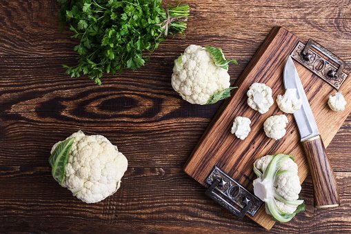 Chou-fleur et chou-fleur haché sur une planche à découper en bois. | Photo : Getty Images