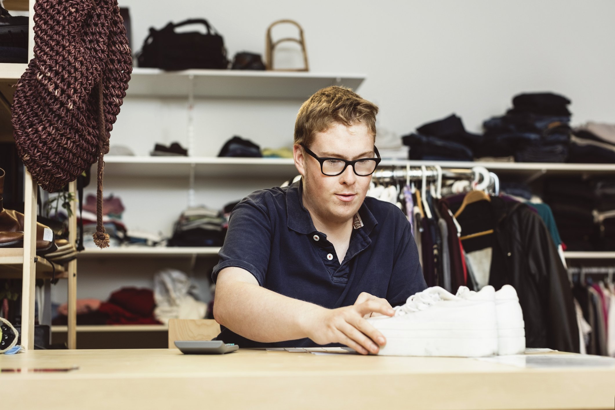 Cashier holding shoes on table while calculating in clothing store. | Photo: Getty Images