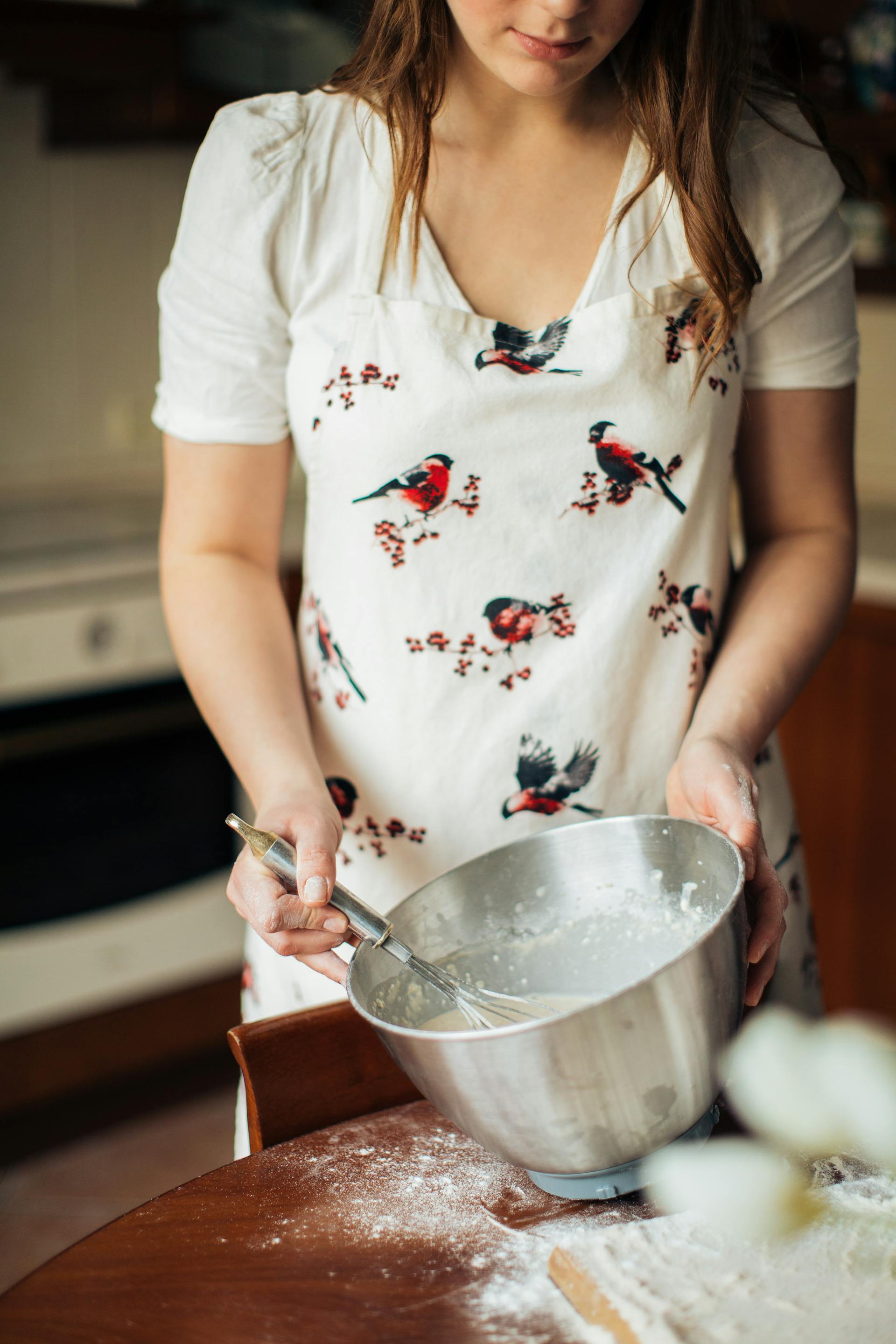A close-up of a young woman mixing ingredients in a stainless steel bowl for baking | Source: Pexels