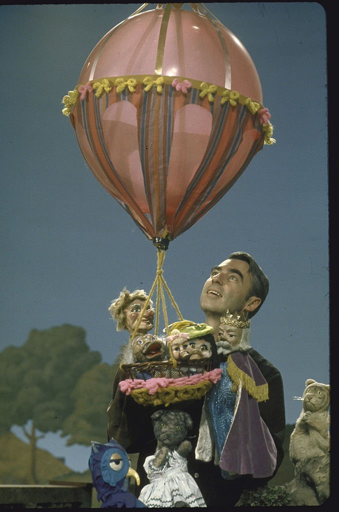 Actor Fred Rogers holding a balloon and puppets in the public TV childrens program Mister Rogers' Neighborhood | Getty Images