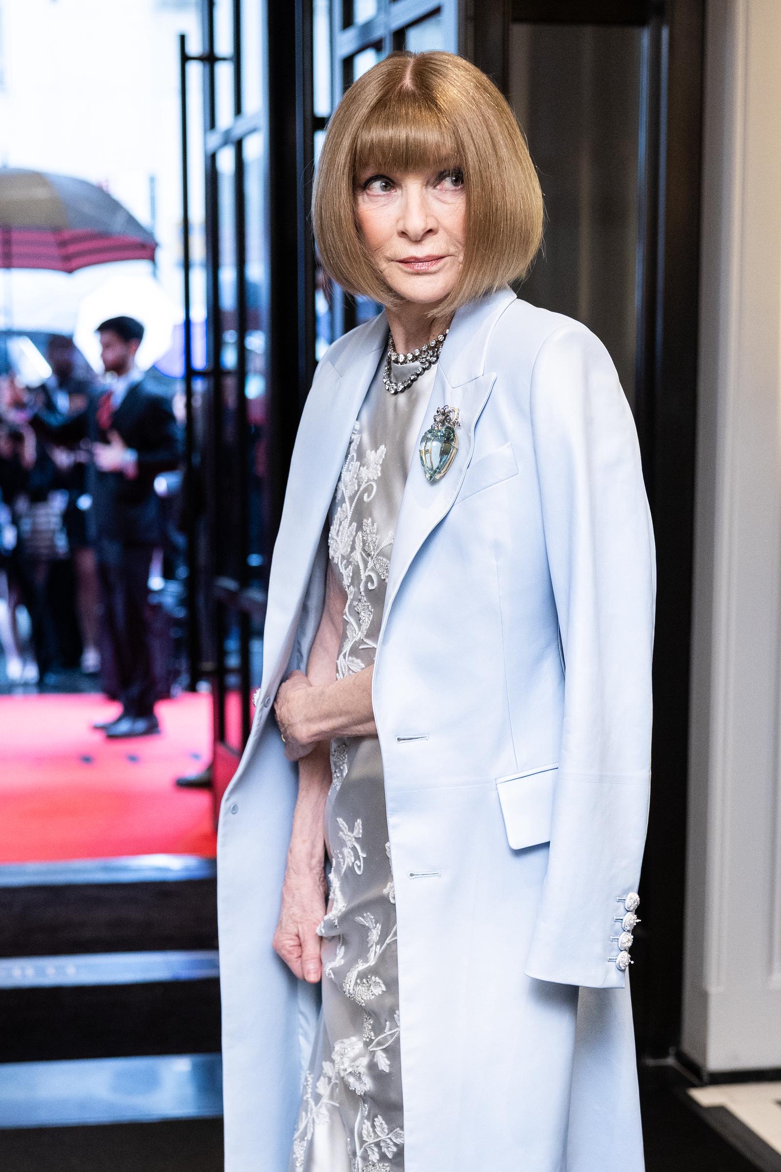 Captured leaving The Mark Hotel, Anna Wintour dons a silk floral gown and powder blue coat, arriving for the 2025 Met Gala celebrating "Superfine: Tailoring Black Style" at the Metropolitan Museum of Art.
