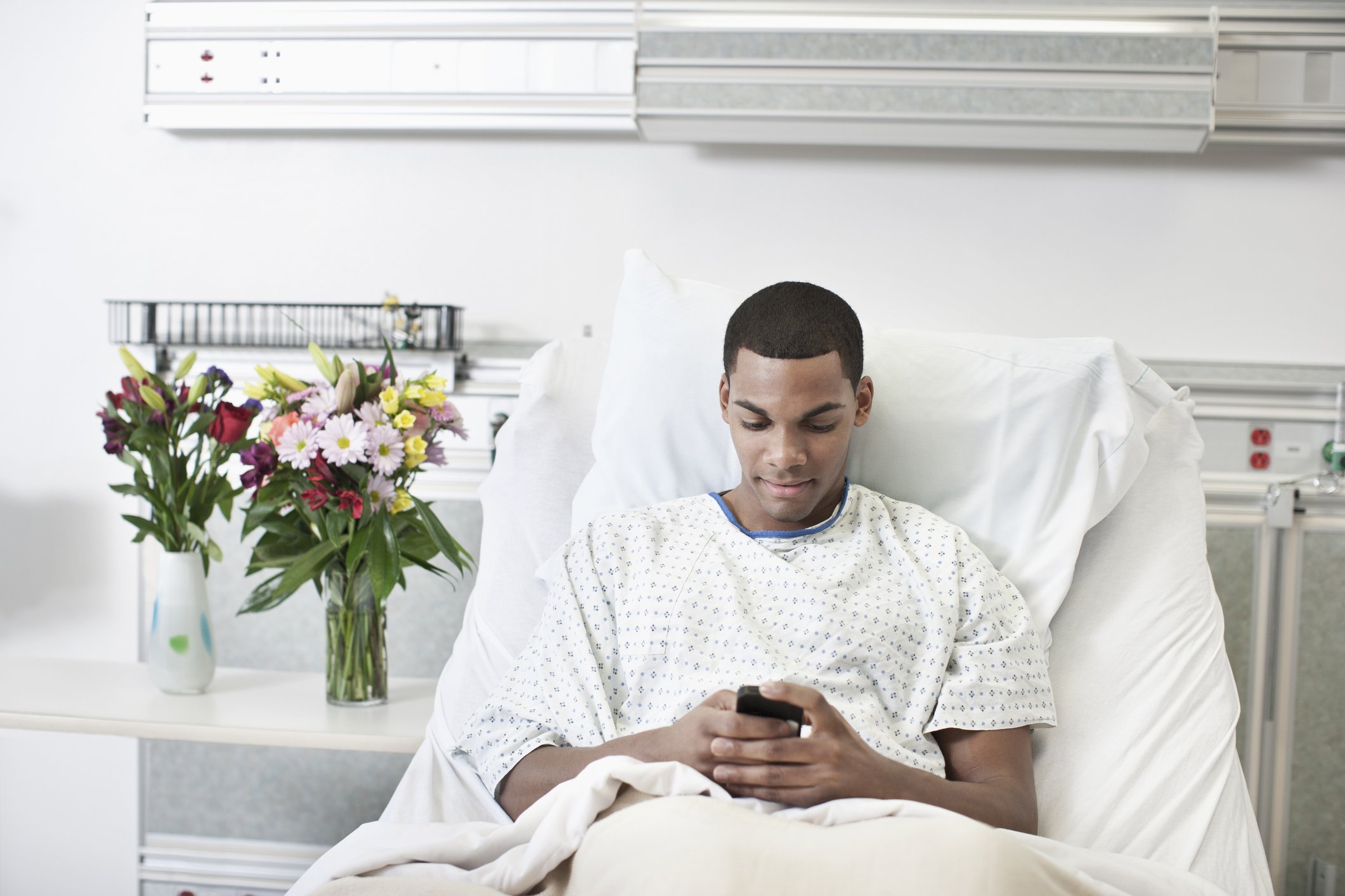 Der Patient benutzt ein Handy im Krankenhausbett. I Quelle: Getty Images