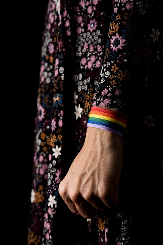 A closeup of a LGBTQ woman with a rainbow-patterned ribbon on her hands. | Photo: Shutterstock.