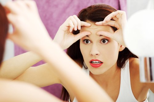 Mujer mirando sus arrugas al espejo| Foto: Shutterstock