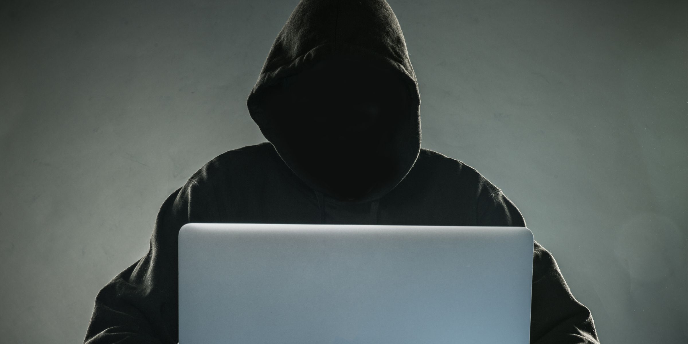 A hacker in a hoodie using a laptop | Source: Shutterstock