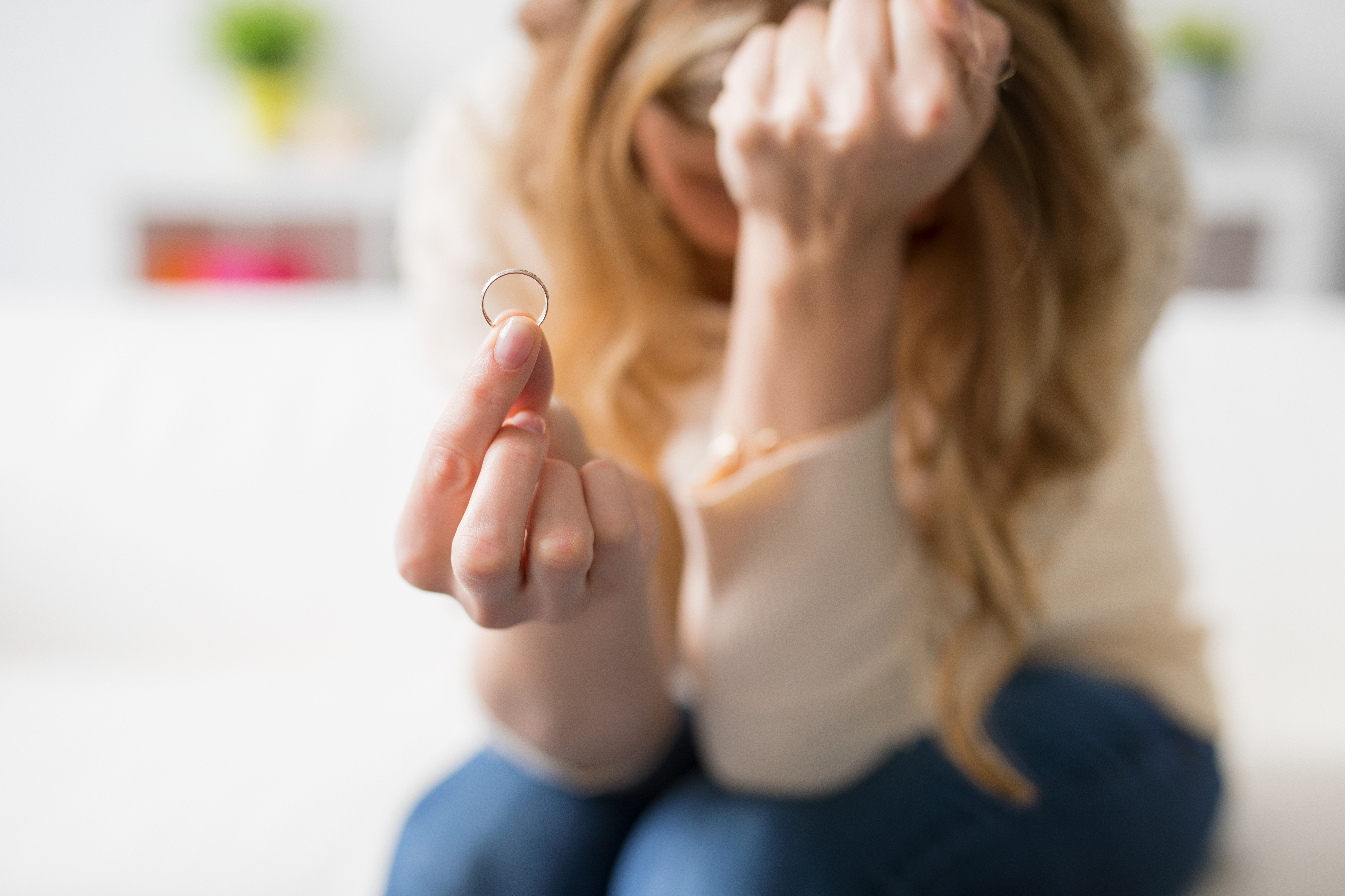 A woman in despair holding out her wedding ring | Source: Shutterstock