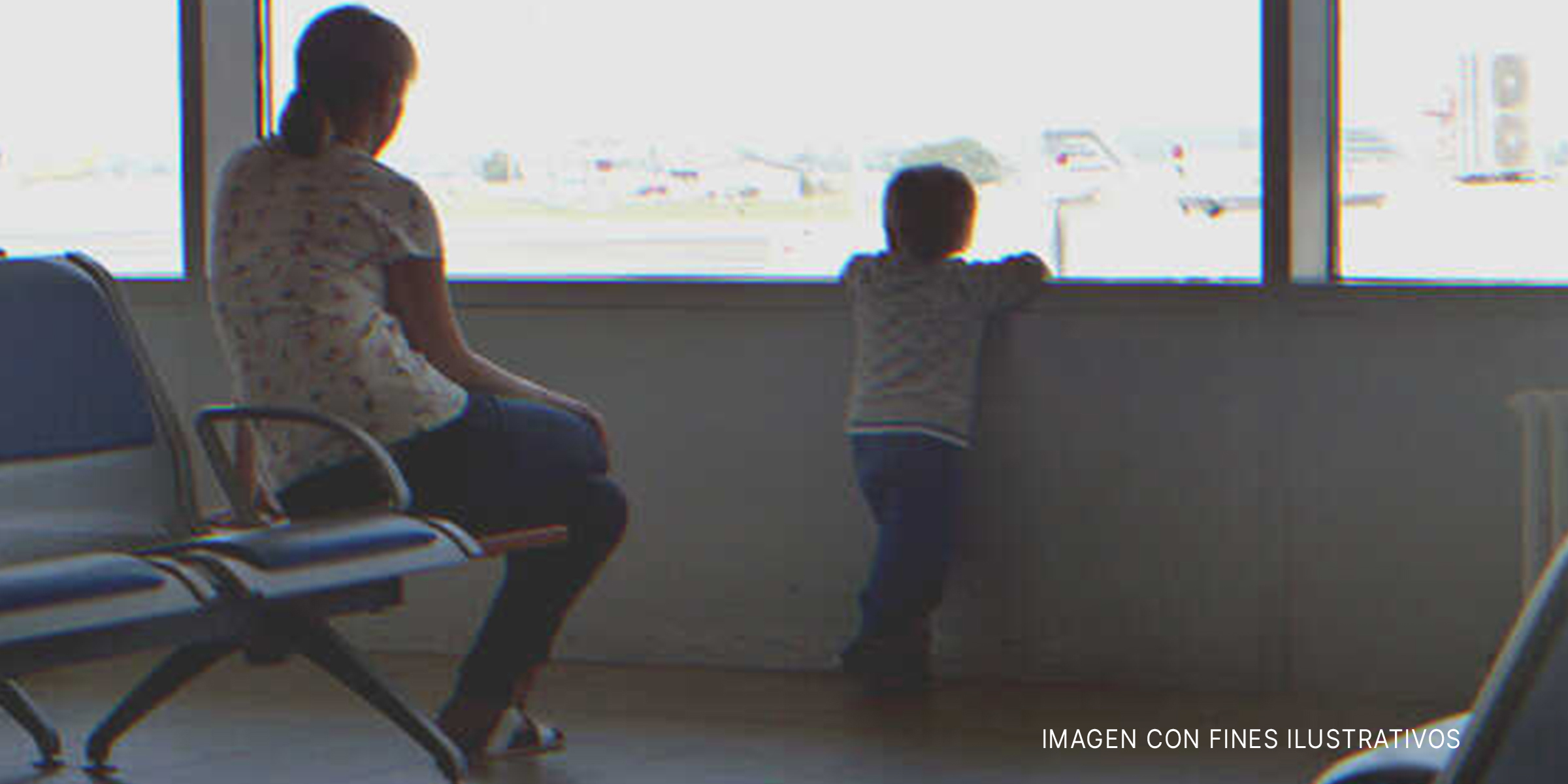 Niño mirando por el ventanal de un aeropuerto junto a su madre. | Foto: Shutterstock