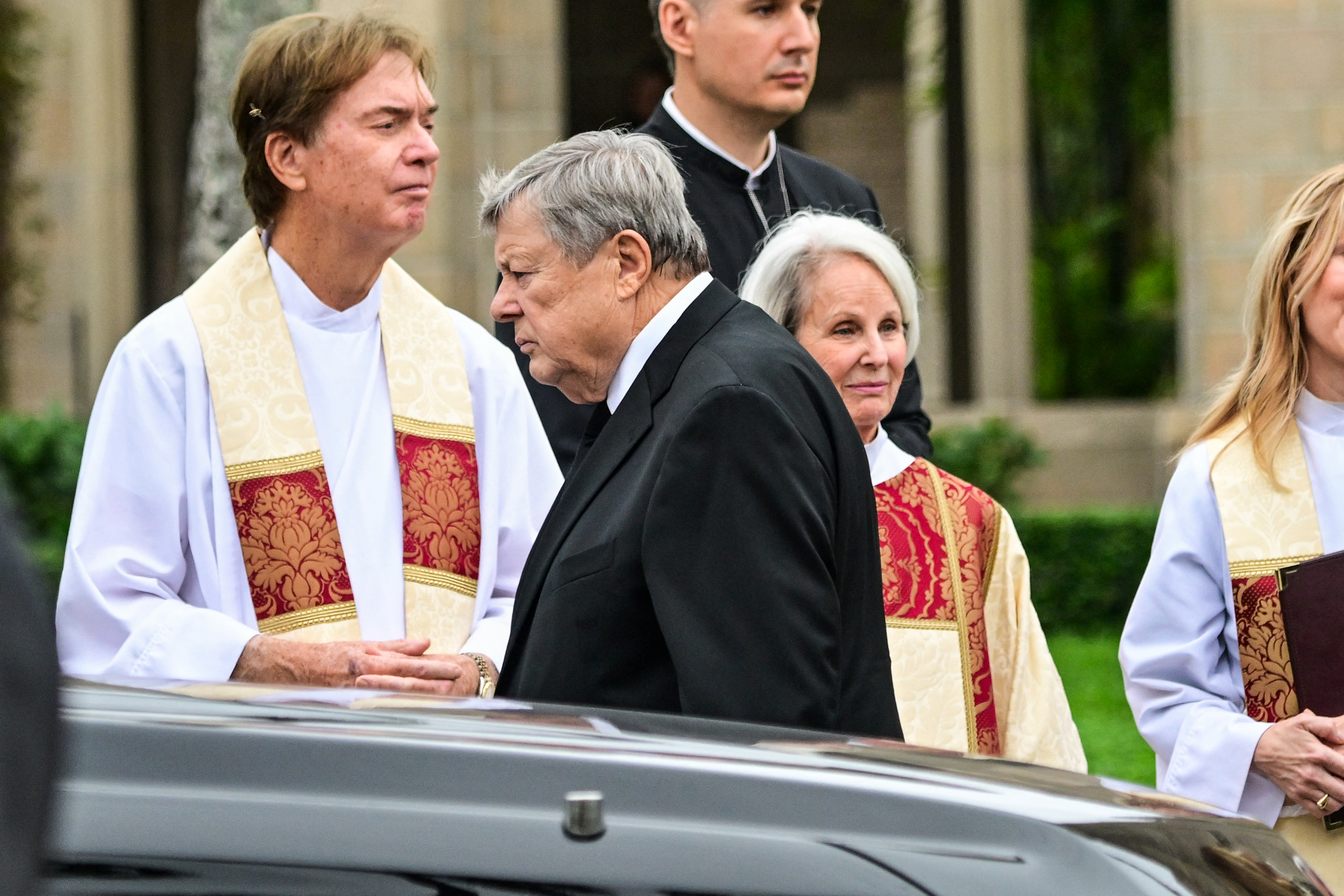 Leaving the church after the funeral, Viktor Knavs pauses to thank members of the clergy who led the service for his late wife. The image captures a quiet moment following the ceremony, with Melania Trump later remembering her mother as "a ray of light in the darkest of days." | Source: Getty Images