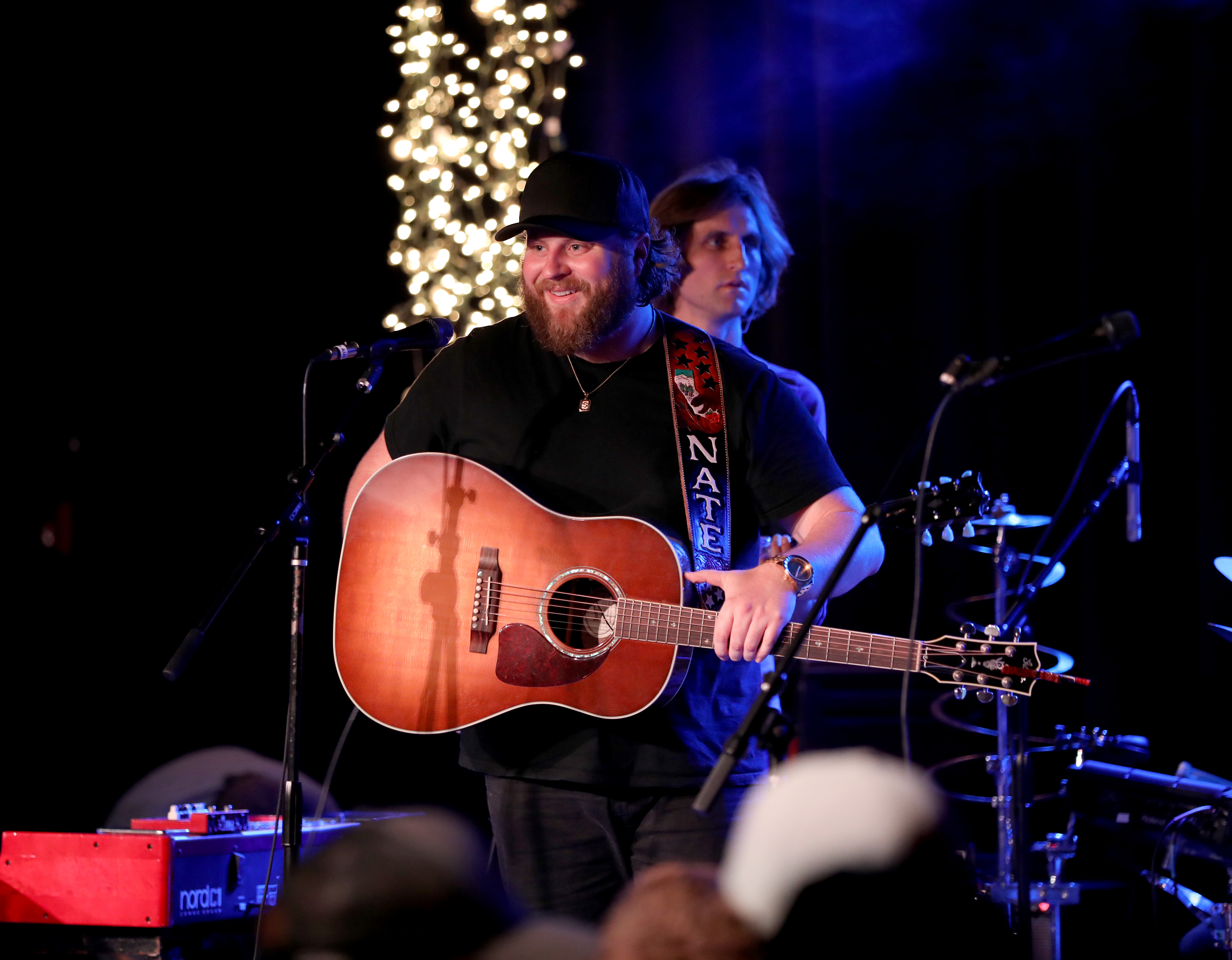 Nate Smith flashes a broad smile between notes, holding his guitar at center stage as the intimate performance takes on a lighter, more playful mood.