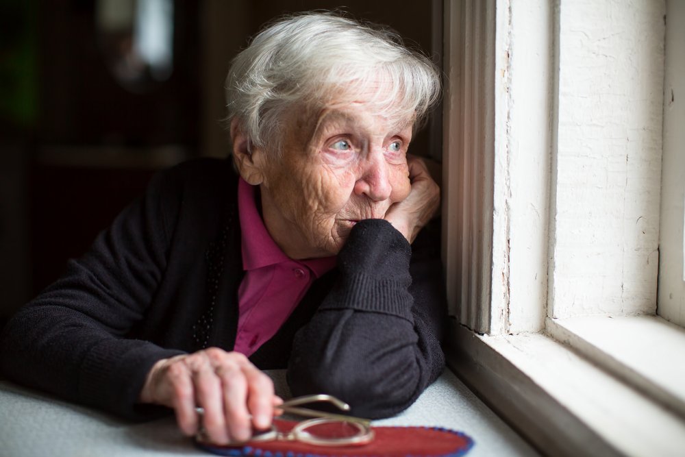 Eine ältere Frau schaut traurig aus dem Fenster. | Quelle: Getty Images